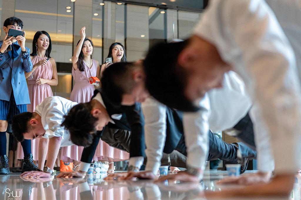 Wedding party members perform pushups while others watch and cheer.