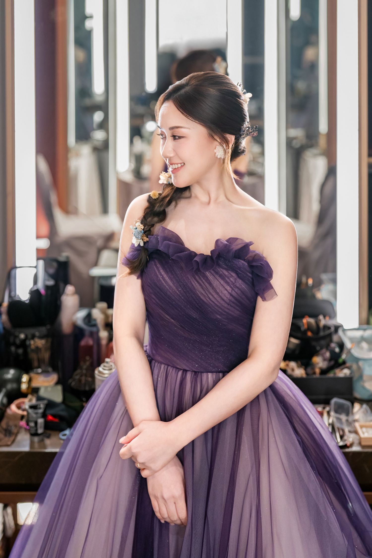 Woman in elegant purple tulle gown poses gracefully in front of mirrored wall at formal event.