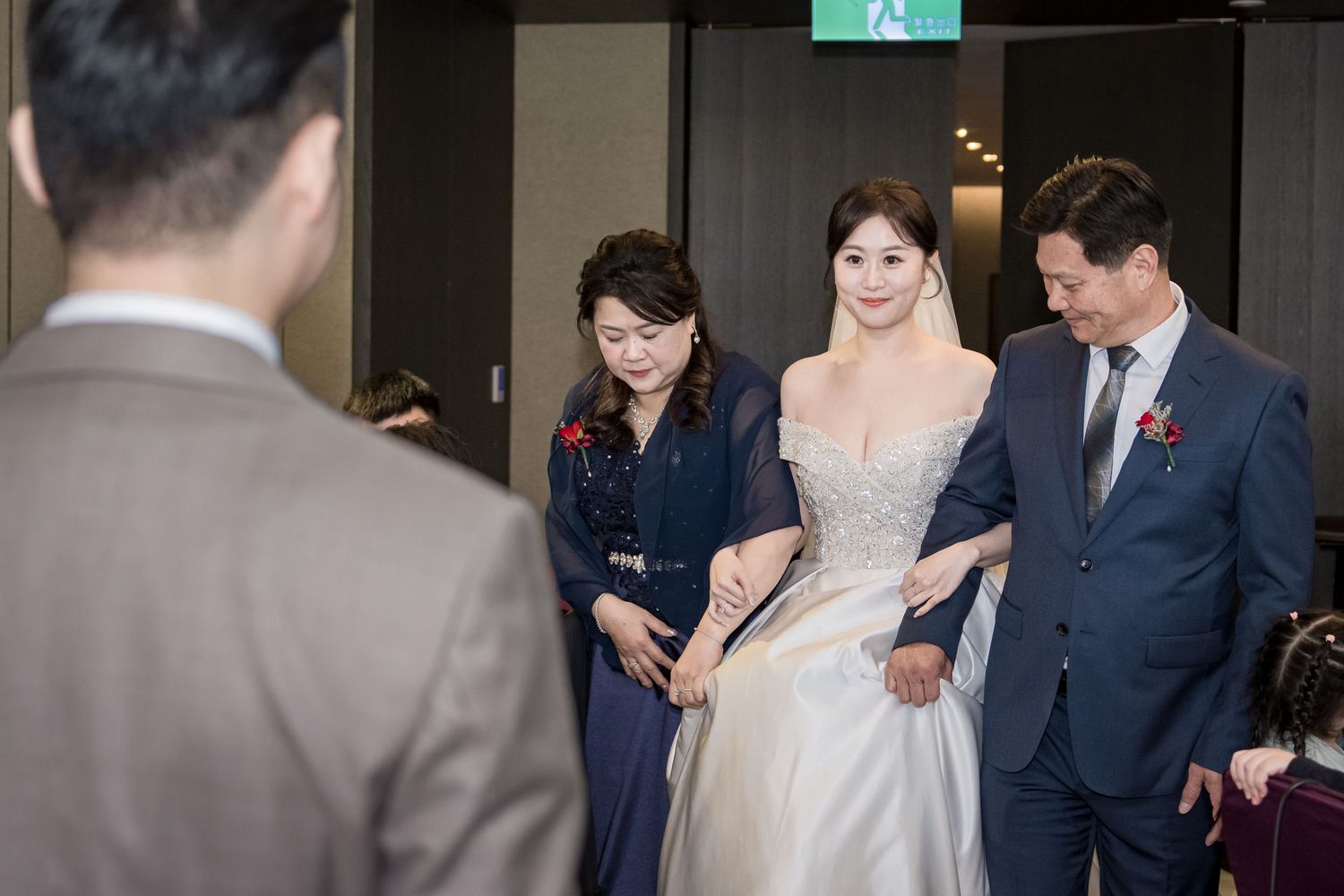 A wedding party gathers for group photos in an elegant indoor venue with modern lighting and decor.