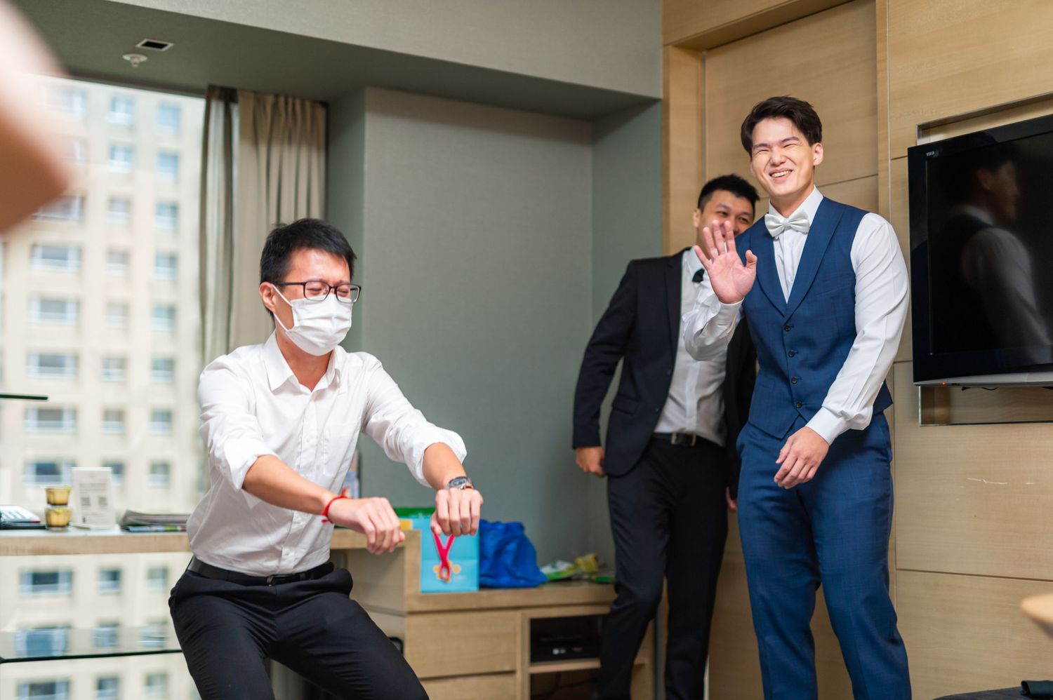 Colleagues in business attire playing in an office space with blurred city view outside the window.