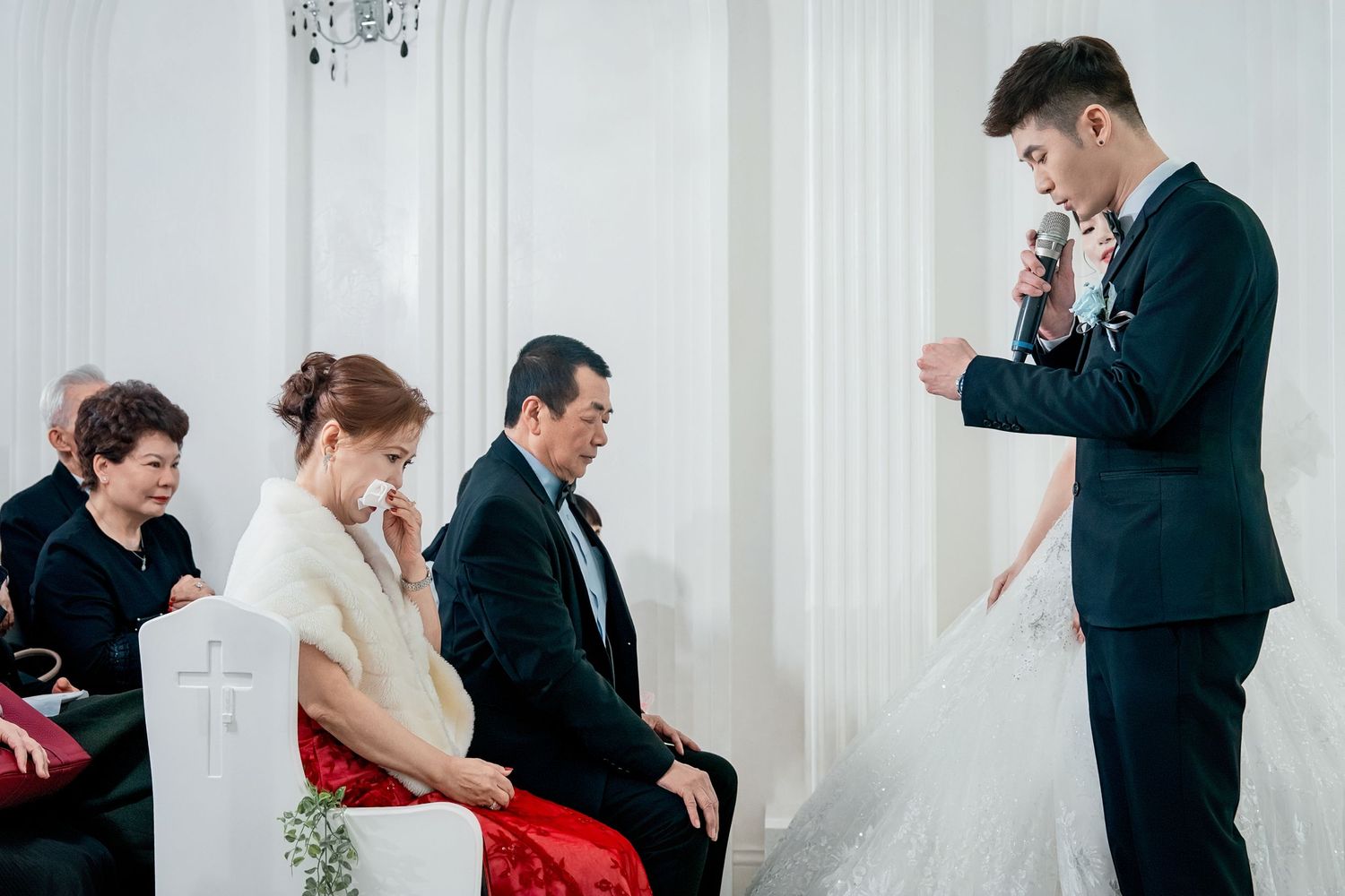 Wedding guests share emotional reactions during a special moment at an elegant indoor ceremony.