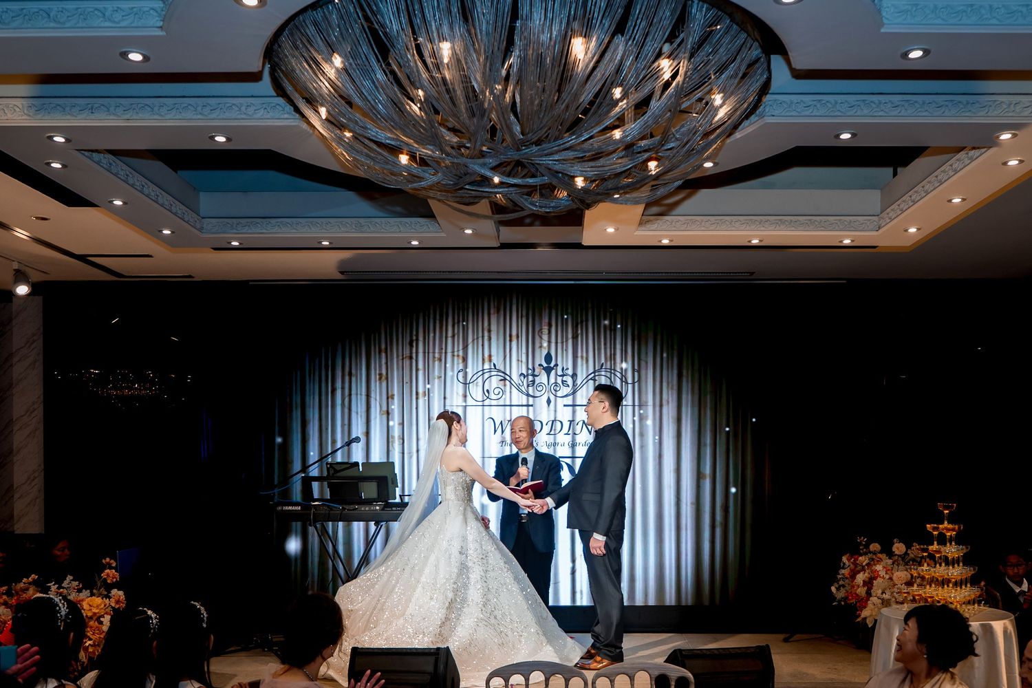 Elegant wedding ceremony and reception venue with crystal chandeliers and white draping decorations.