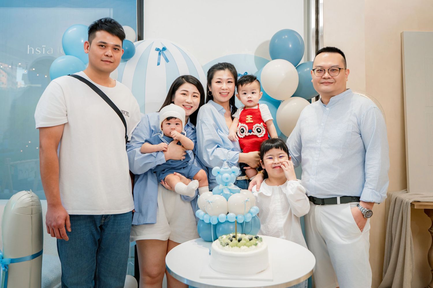 A collage of birthday party photos with blue and white decorations and a white cake.