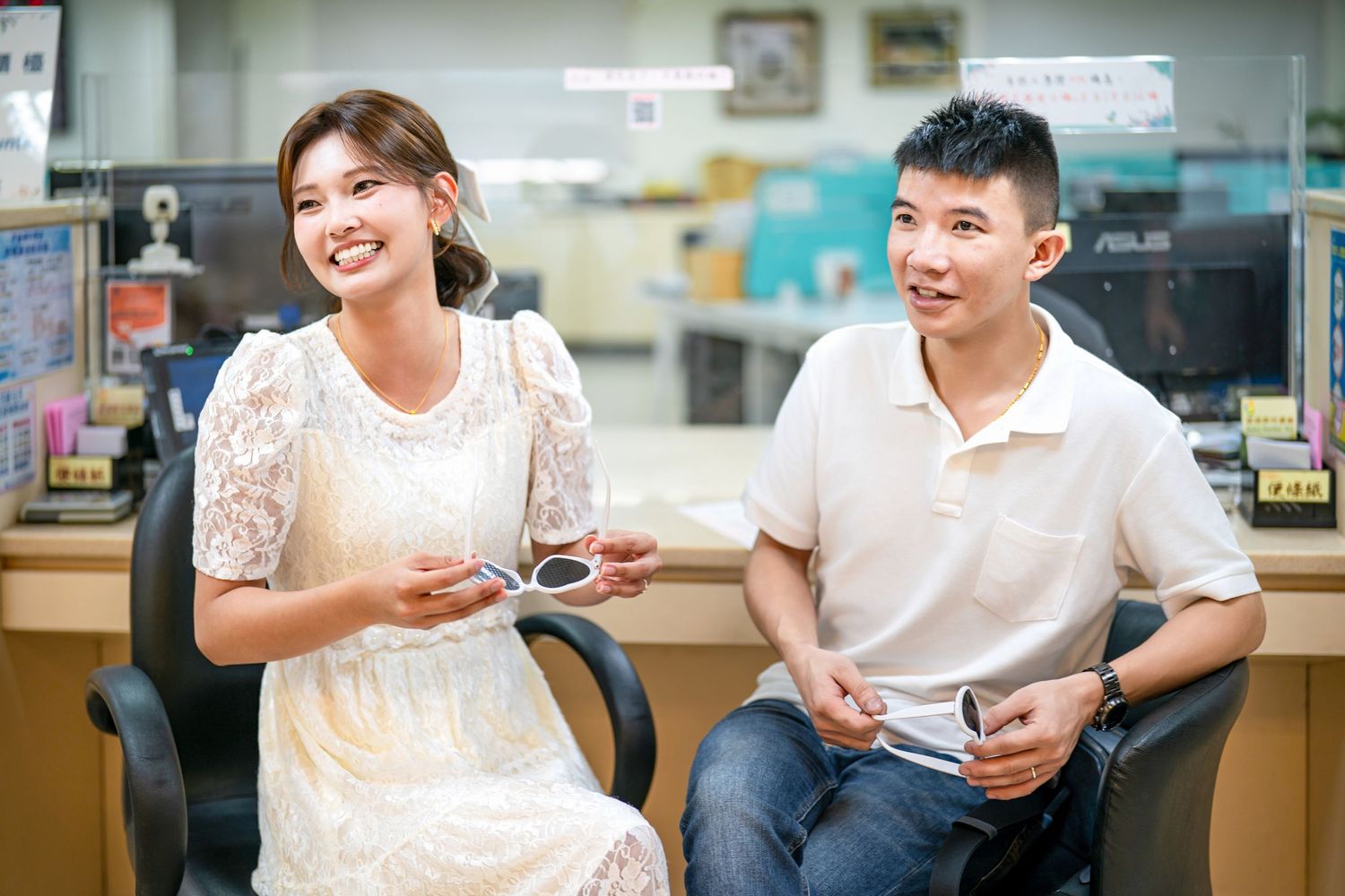 Students in white shirts sit together at a table in a casual setting, engaged in conversation and using phones.