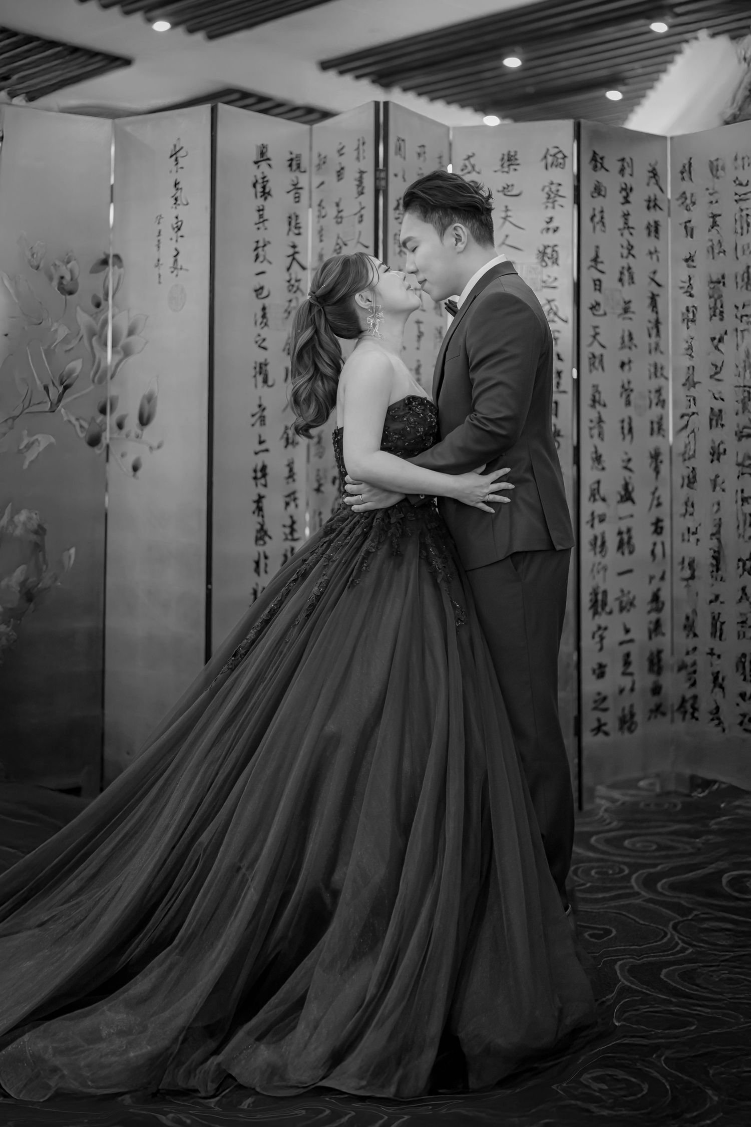 A romantic black and white photo series showing a couple in formal attire posing against a wall with Chinese calligraphy.