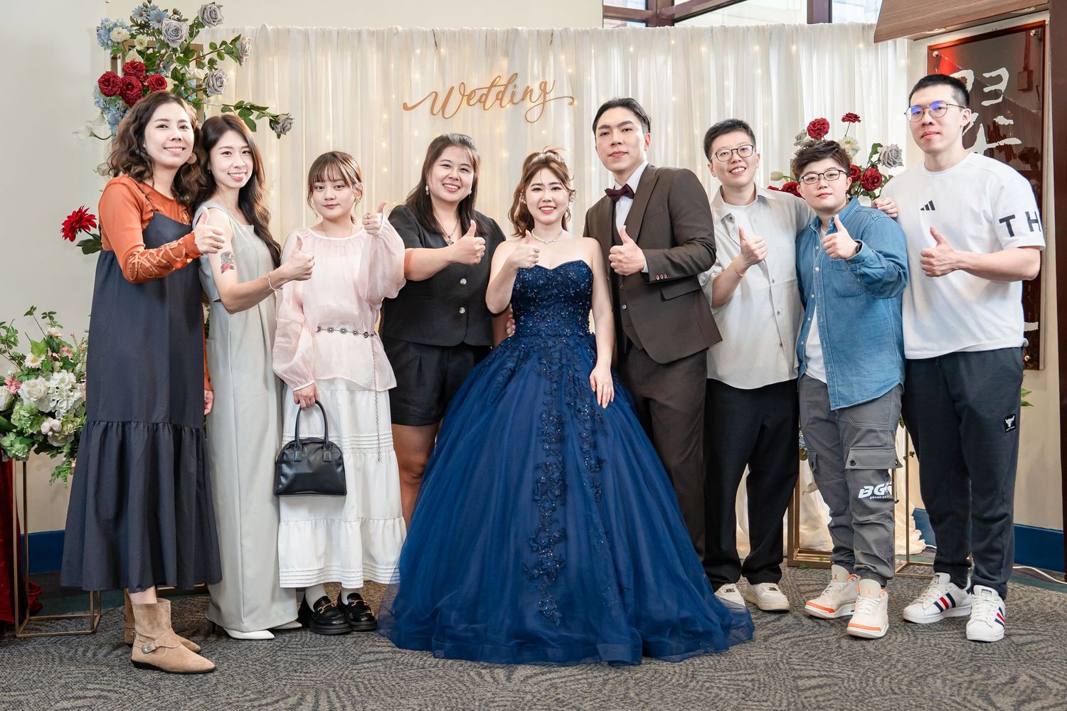 A group of people gathered at a celebration event with someone wearing a stunning royal blue ballgown as the centerpiece.