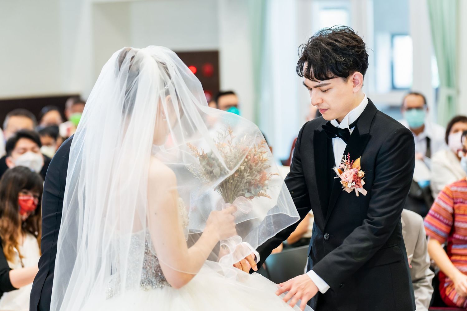 Intimate wedding ceremony moment showing couple in traditional white dress and black tuxedo.
