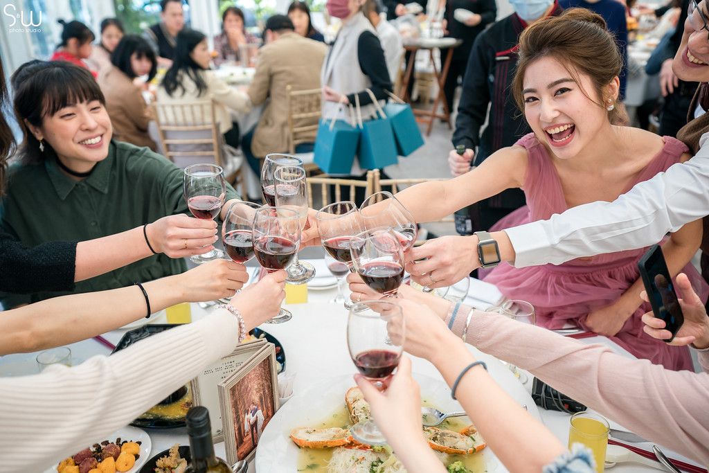 A celebratory toast at a reception with guests raising wine glasses around a decorated table.