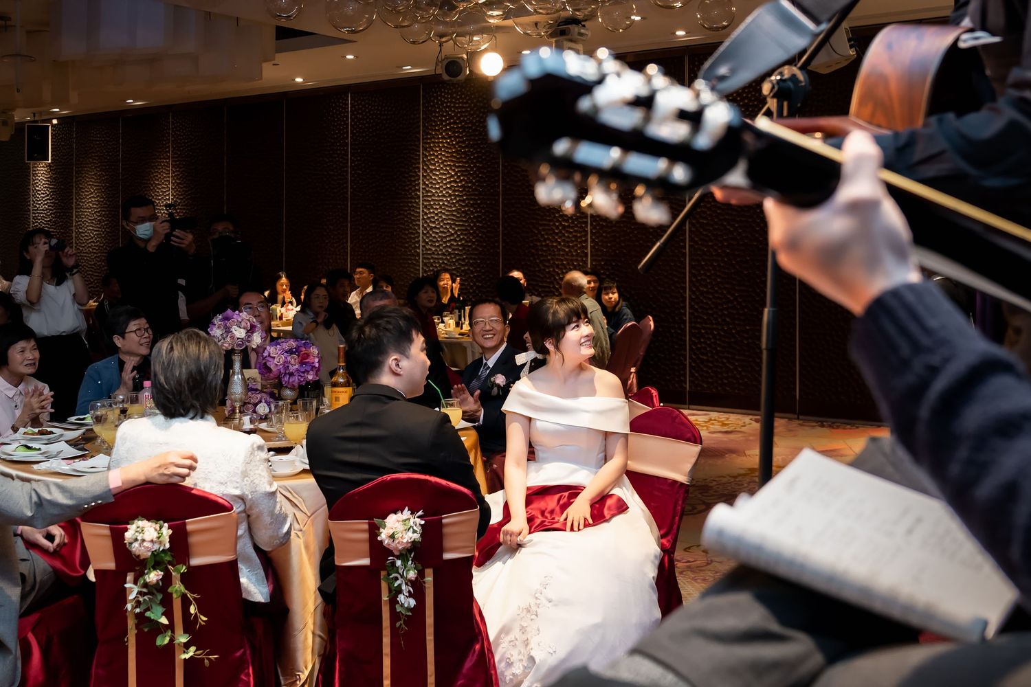 A videographer films a couple at their wedding reception while guests dine.