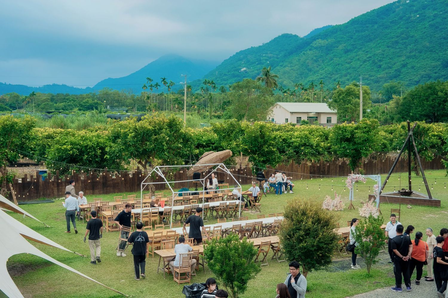 People gather at an outdoor recreation facility with mountains and lush greenery in the background.