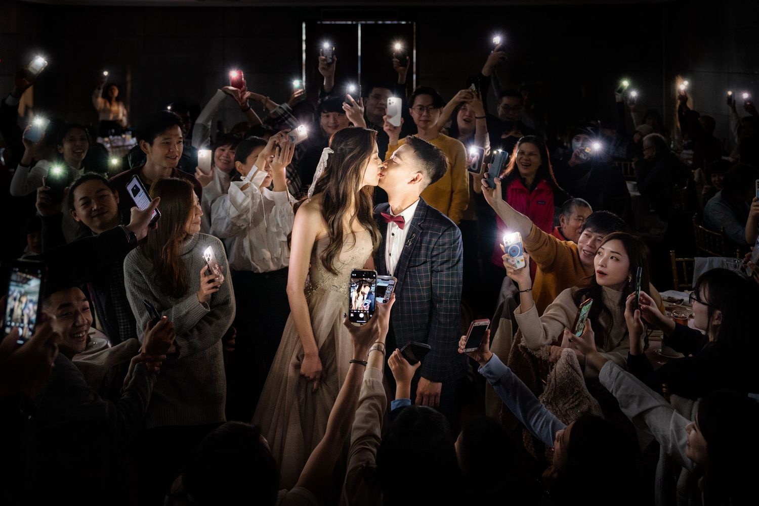 A crowd of concert-goers holding up phones with flashlights in the dark during a nighttime performance.