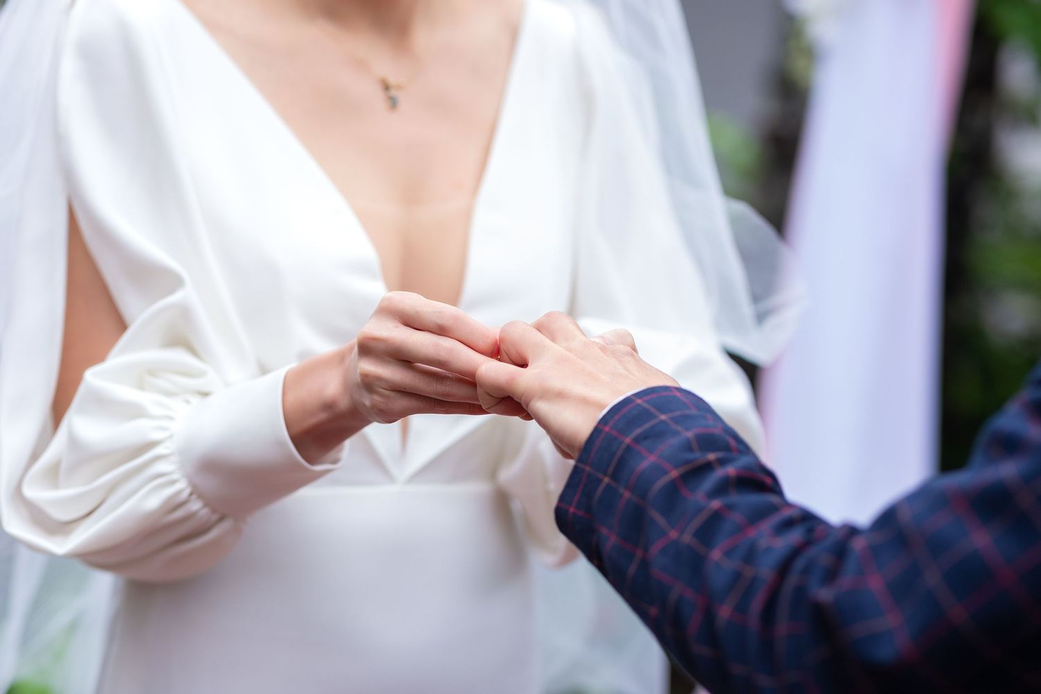 A close up view of hands exchanging wedding rings during a wedding ceremony.