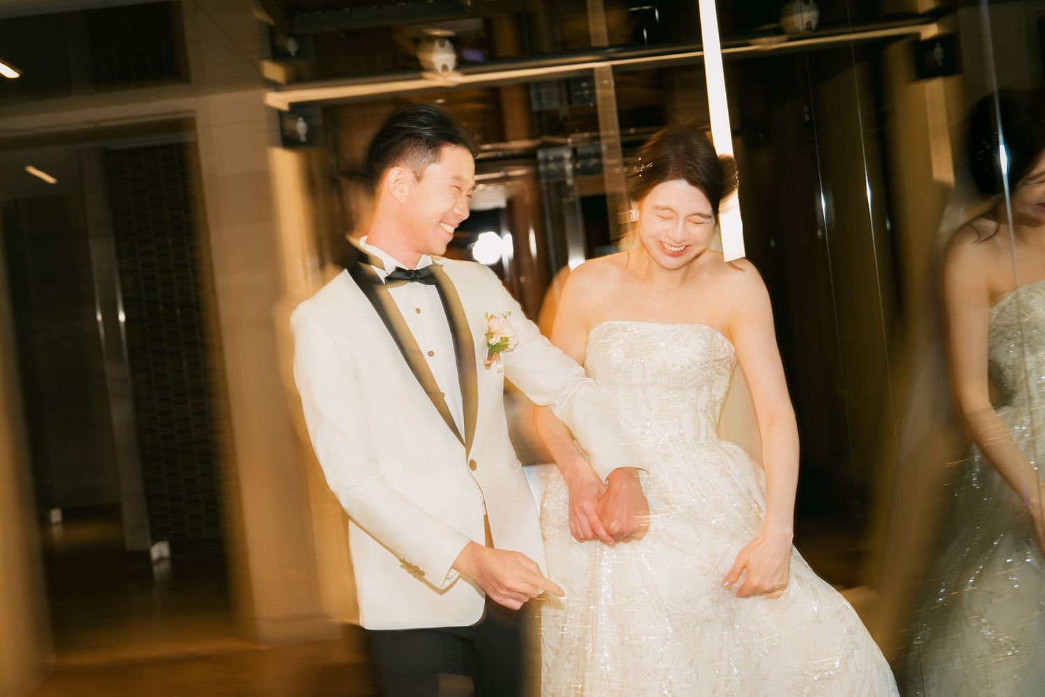 Wedding guests dance and celebrate during a lively reception in an elegantly lit indoor venue.