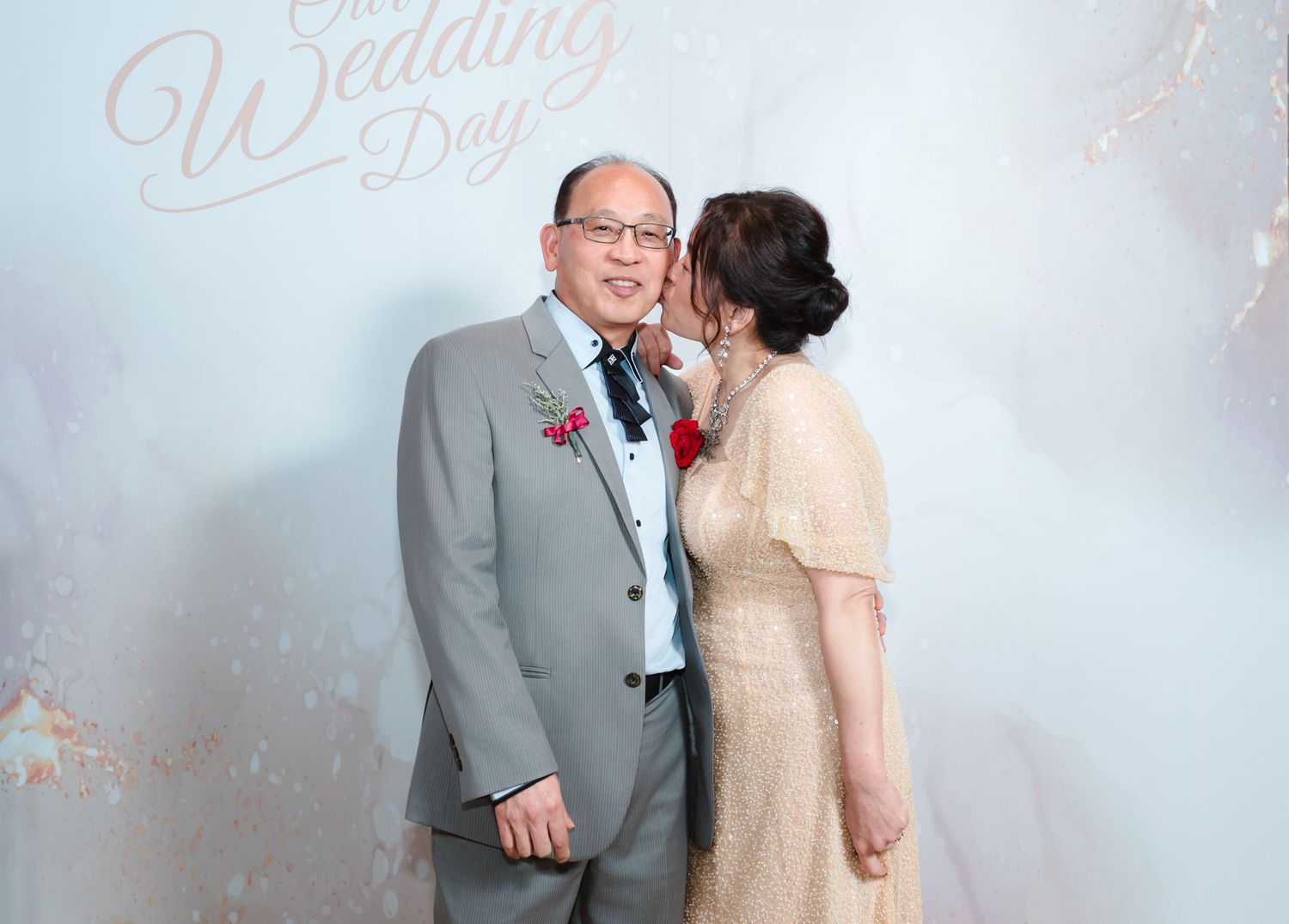 A joyful couple in formal attire share an intimate moment against a dreamy light backdrop at their wedding celebration.