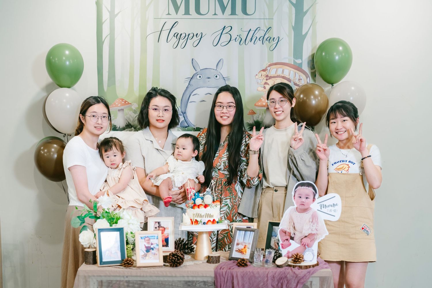 A birthday celebration party setting with balloons, cake and decorations around a table with people enjoying festivities.