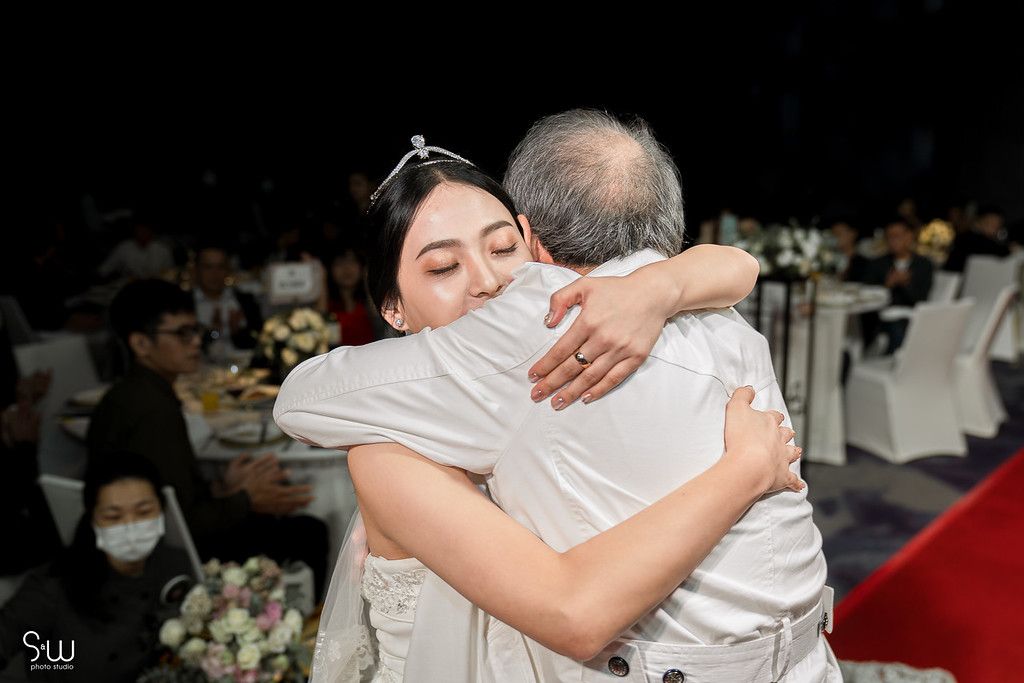 Touching emotional embrace during wedding reception captured in black and white tones.