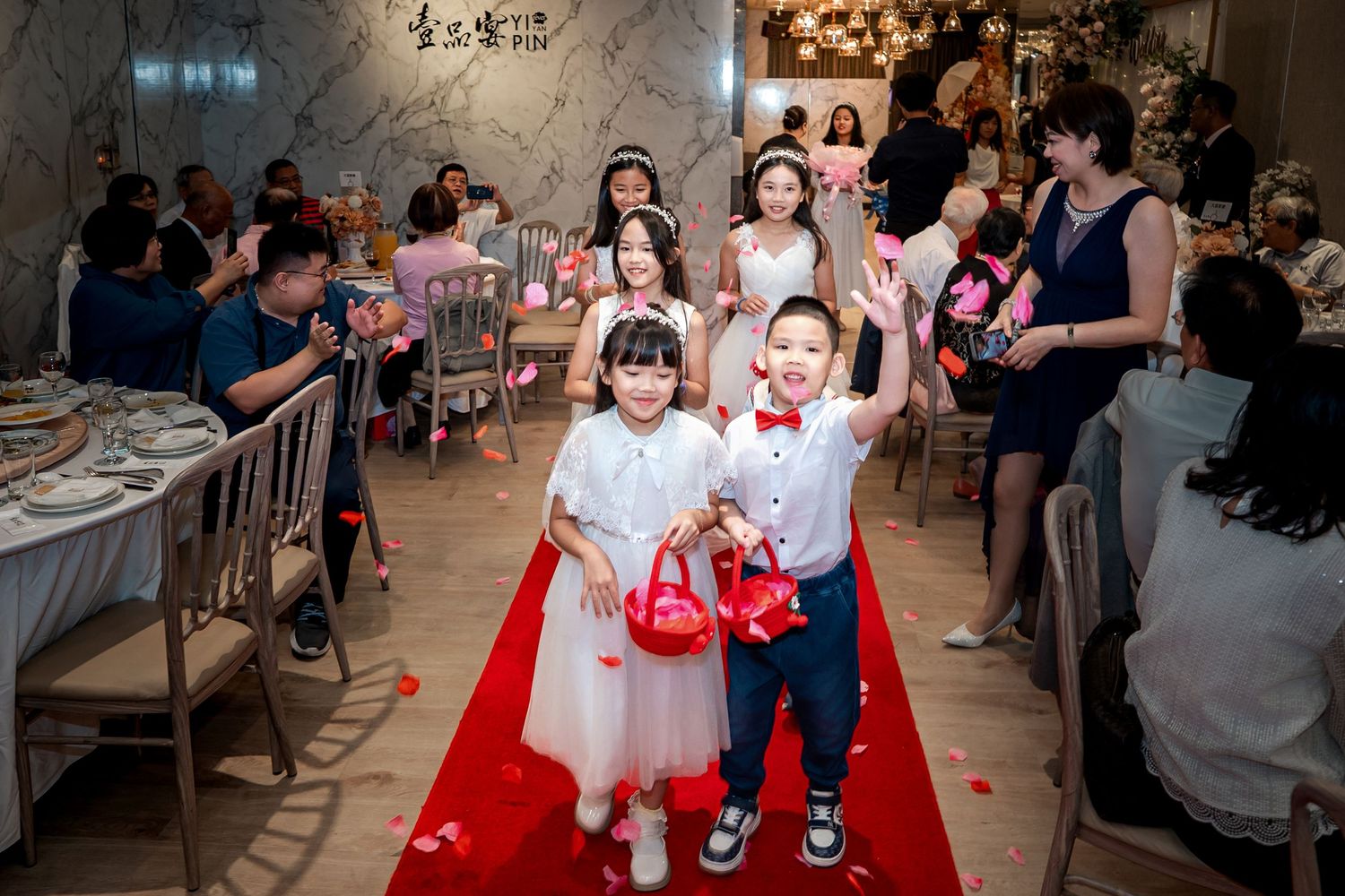 Wedding reception guests dancing and celebrating on a dance floor with festive lighting and decorations.