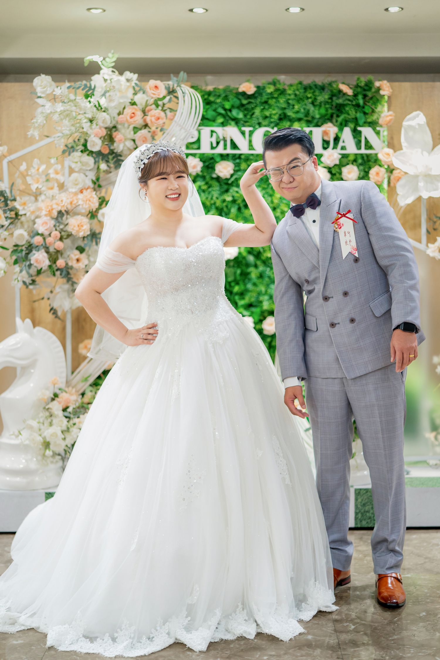 A couple in wedding attire shares joyful moments in a beautifully decorated venue with floral arrangements and greenery.