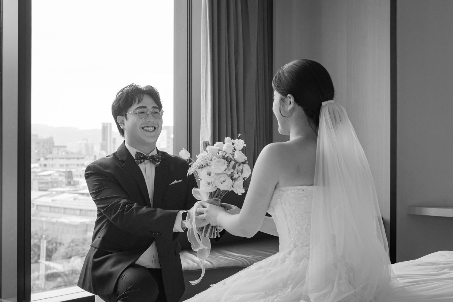 Bride and groom share a tender moment during their wedding ceremony at a modern venue with city views.