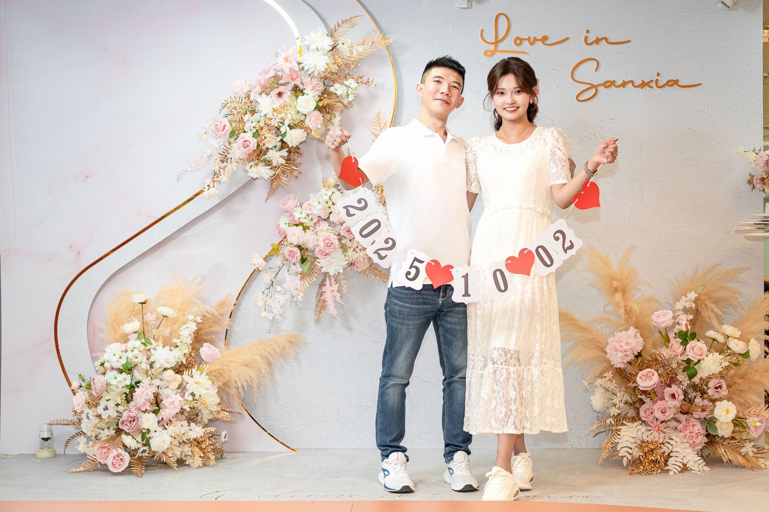 Romantic engagement photo session with floral arch decorations and soft pink and cream color palette.