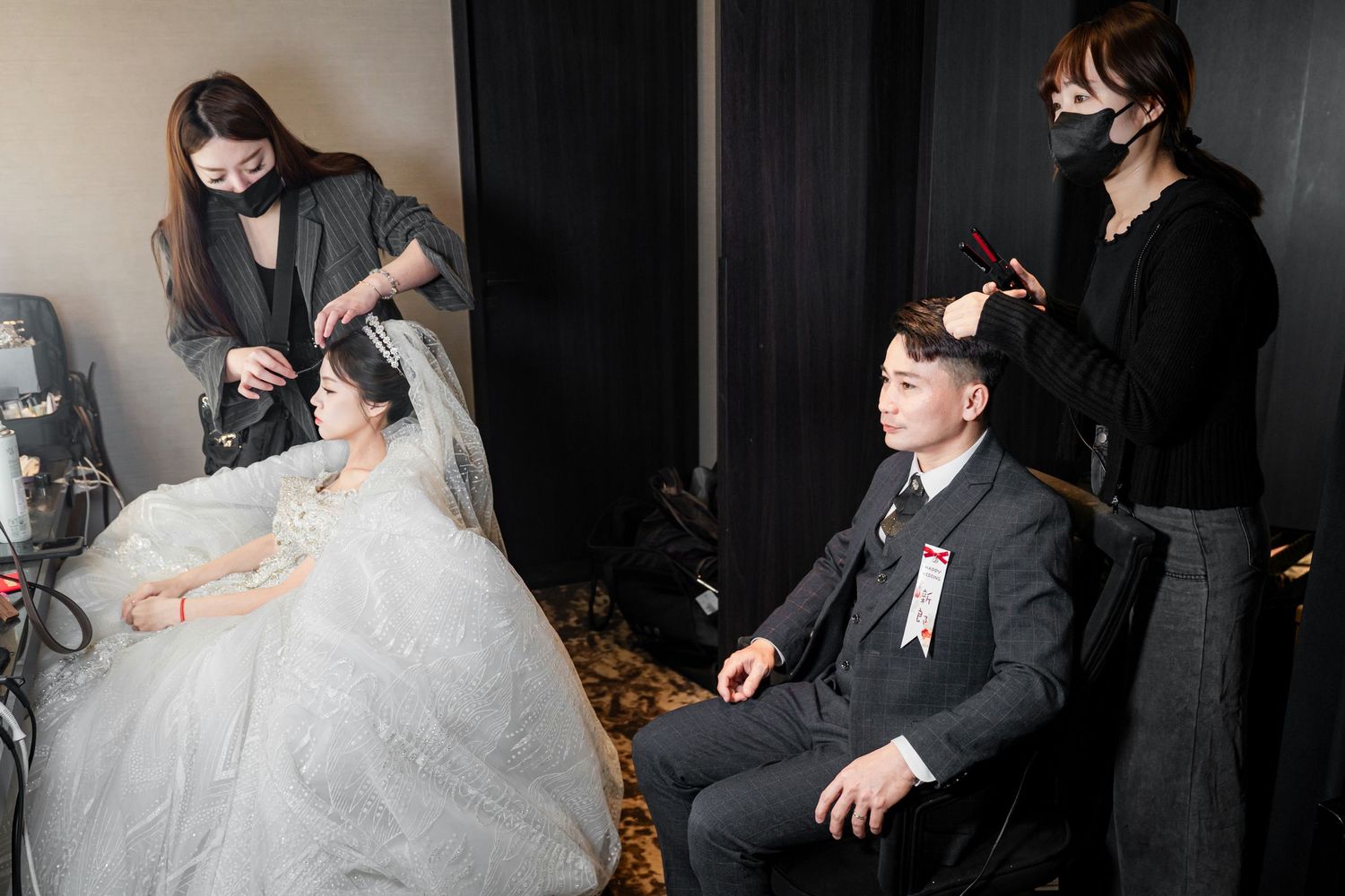 Wedding preparations in progress as stylists work with a bride and groom before their ceremony.