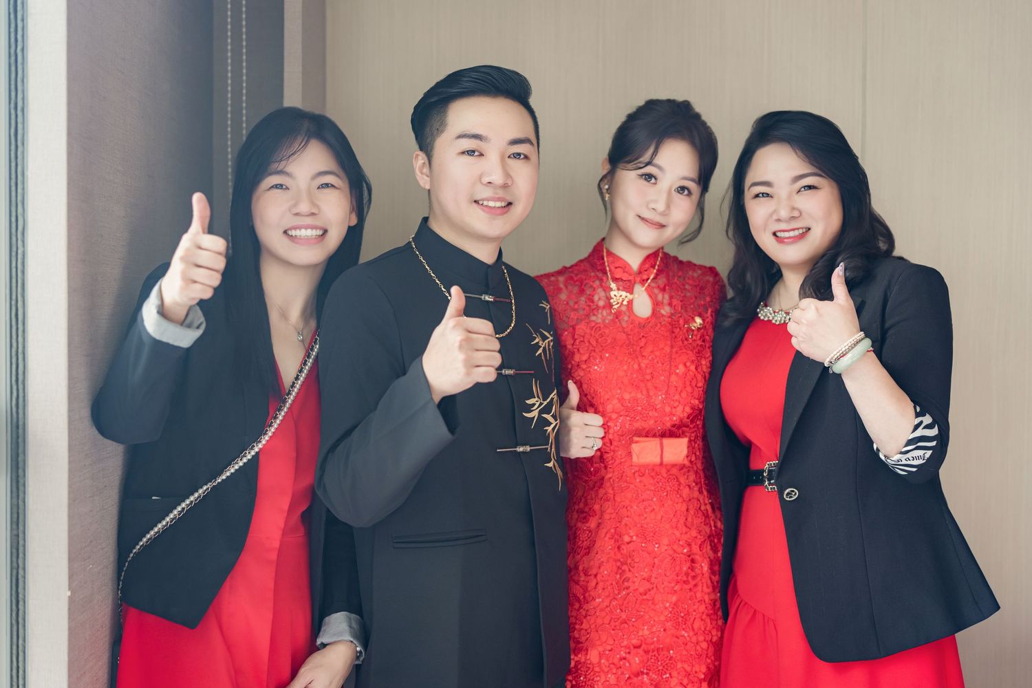 A group wearing red and black formal attire poses together with thumbs up gestures.