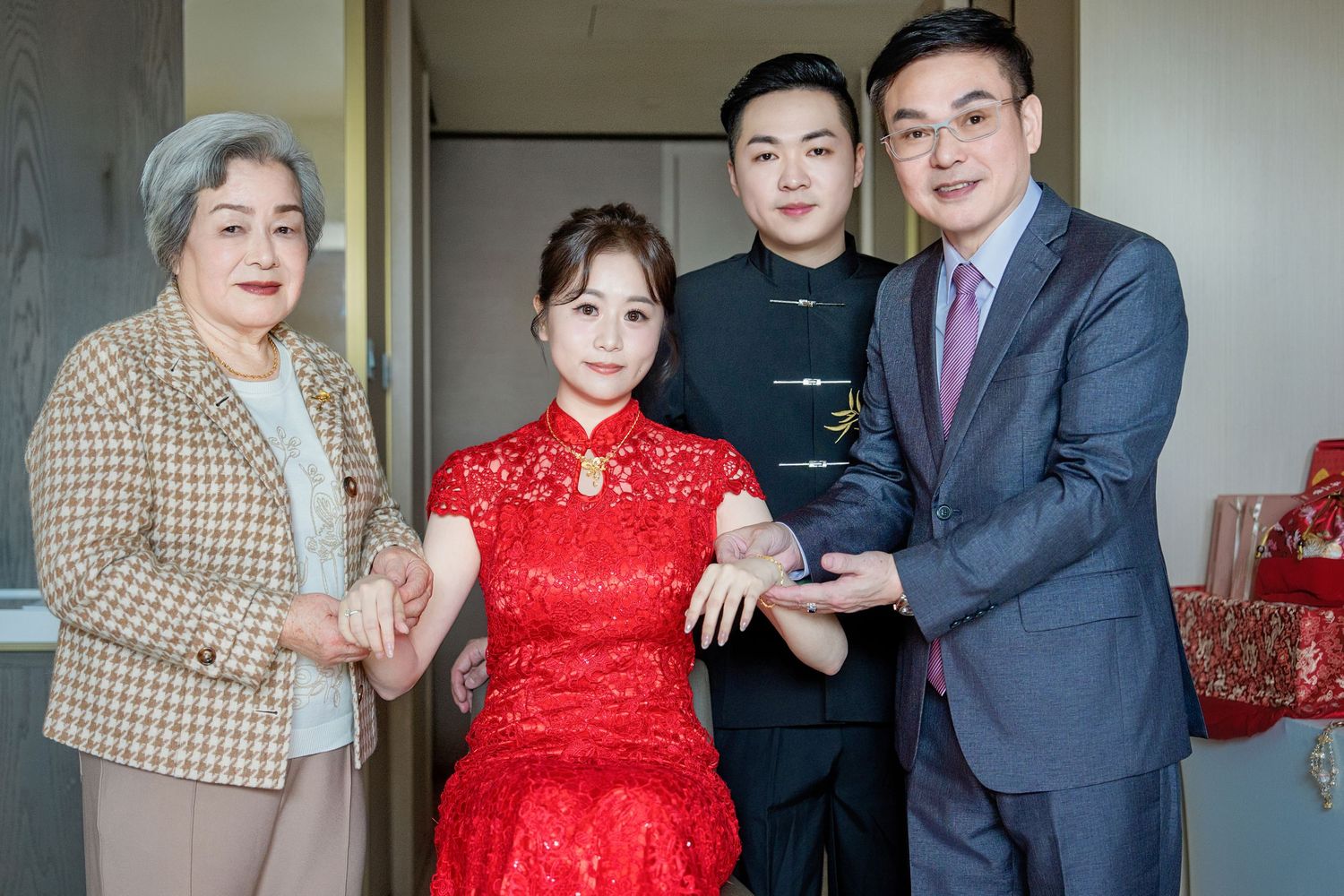 A group of people in formal attire pose together at a traditional Chinese wedding celebration.