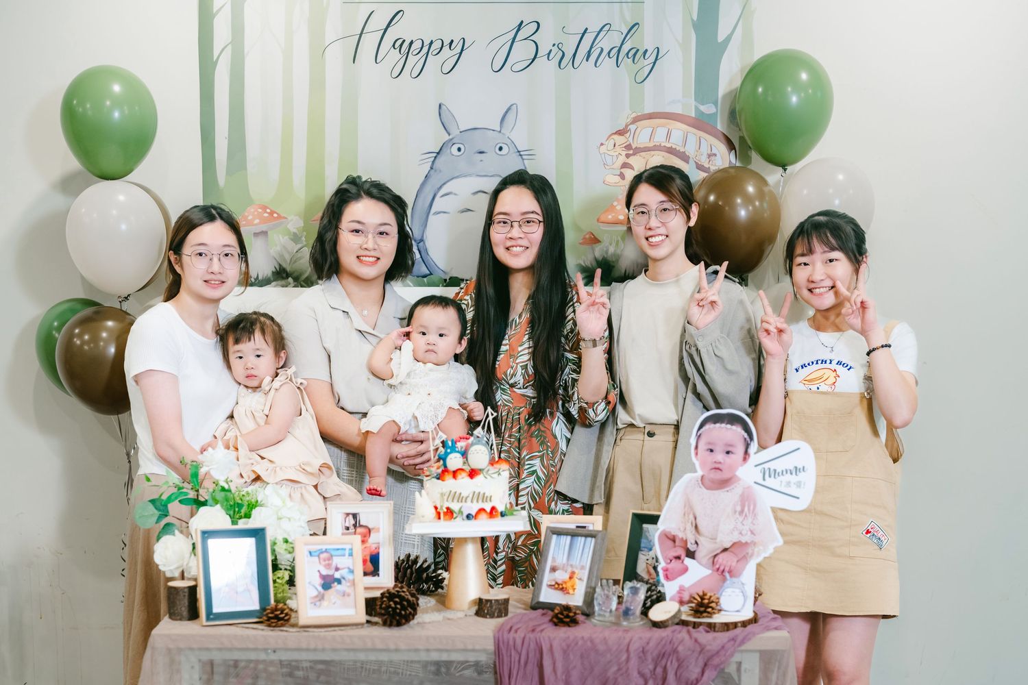 A birthday celebration scene with festive green and white balloons, cakes, and decorations.