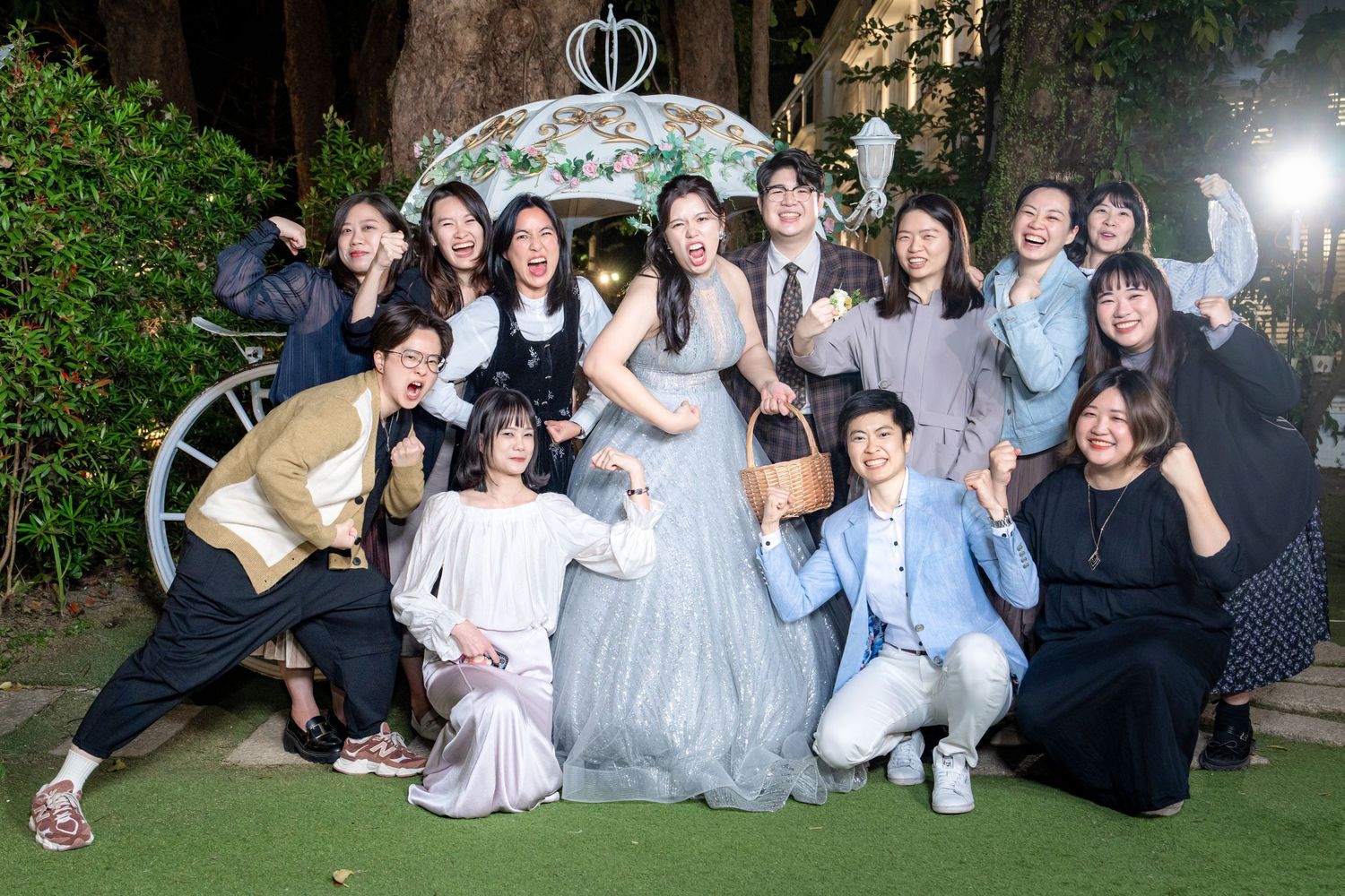 A group of people in casual attire gather together outdoors for a nighttime photo.
