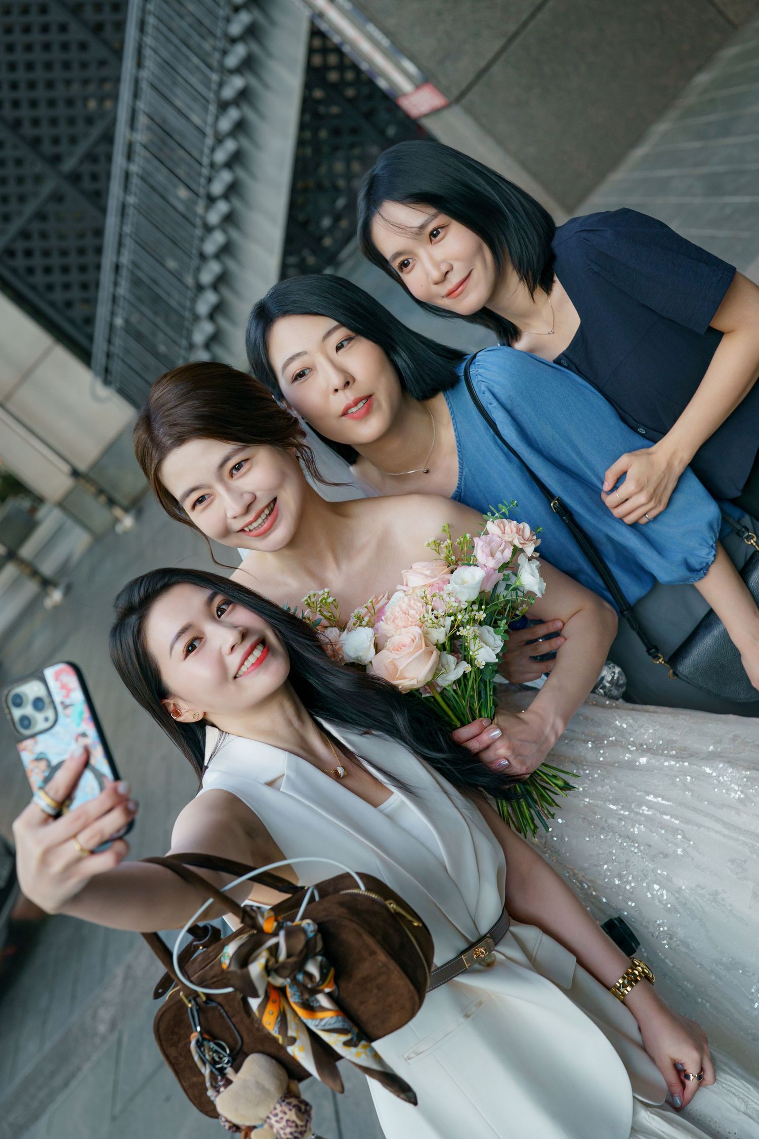 Young couple poses and takes selfies together in wedding attire with candid expressions and floral bouquet.