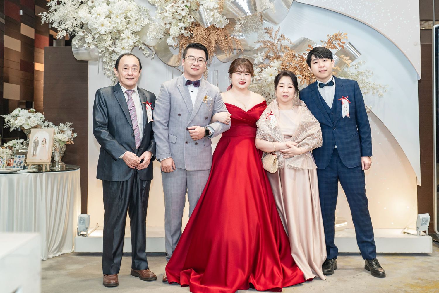 Wedding party gathers in elegant venue with crystal chandeliers and floral arrangements.