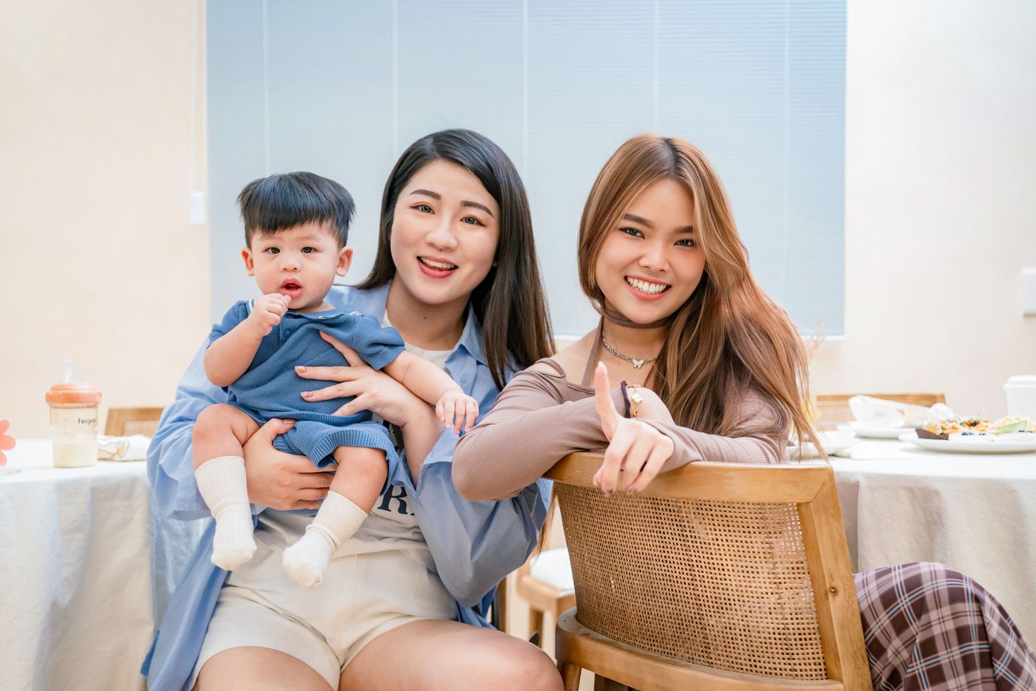 A happy Asian family relaxes together at home on a comfortable couch in a bright living room.