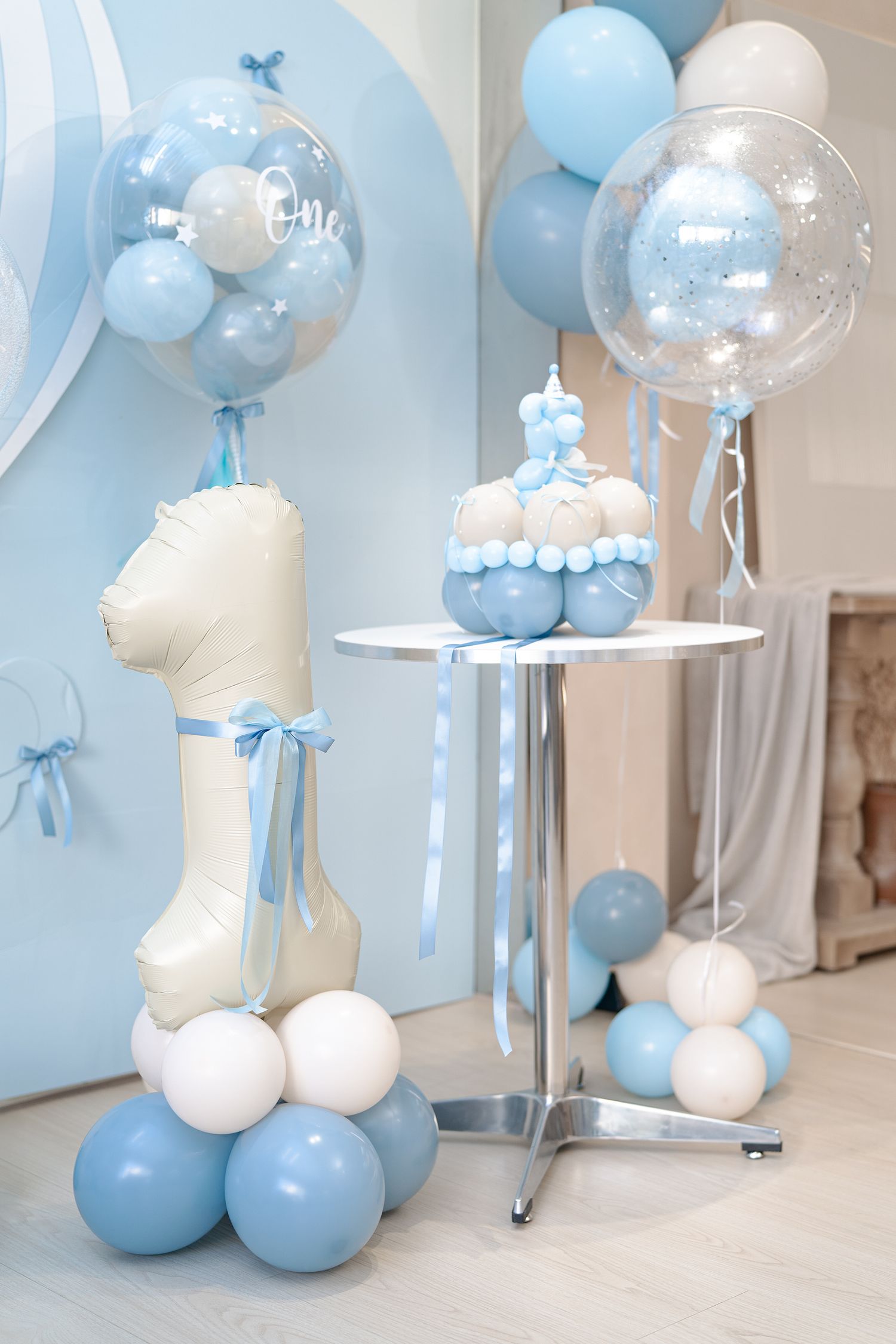 Baby shower decorations featuring blue and white balloons with clear bubble balloons and elegant party accessories.