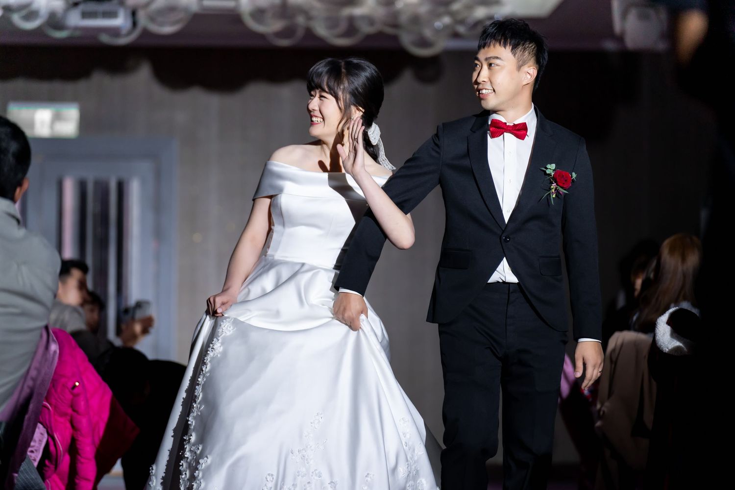 Reception entrance with couple in white wedding dress and black tuxedo with red bowtie.