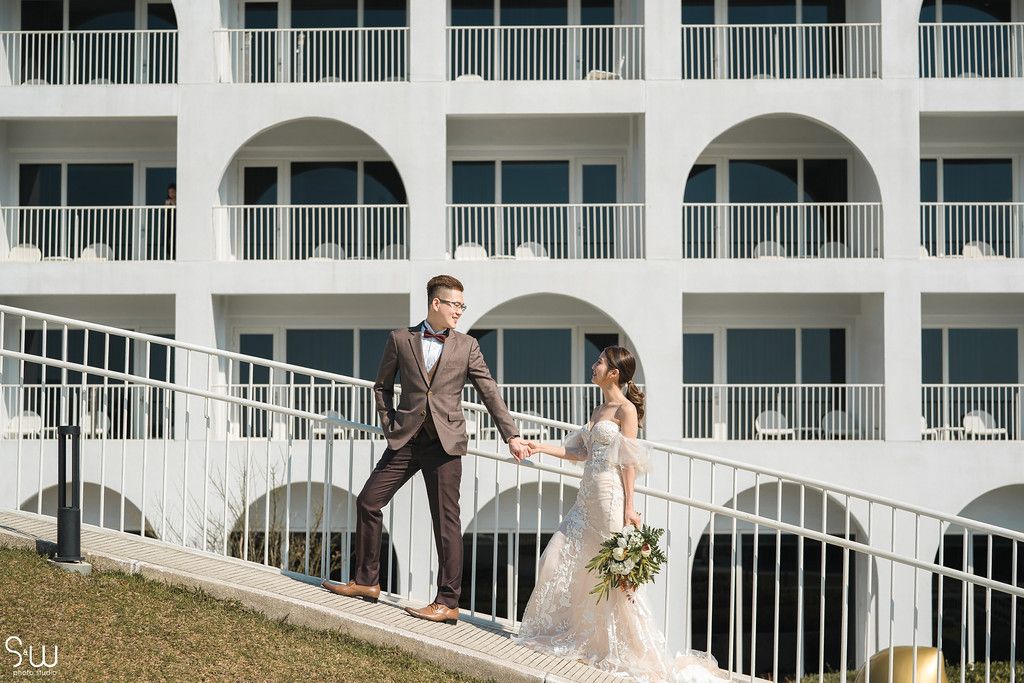Happy couple walking down white spiral staircase at elegant Mediterranean-style venue.