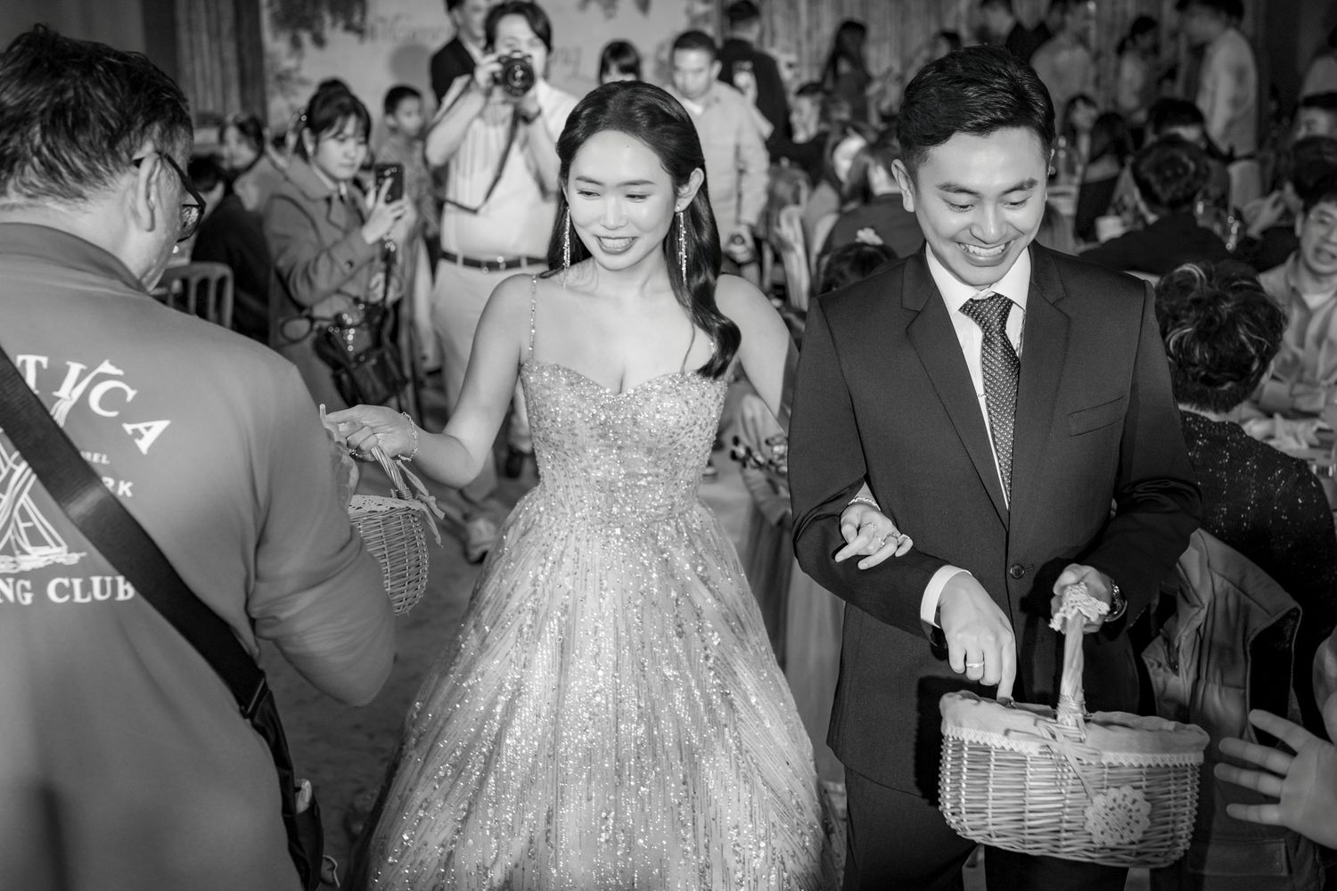 A couple at a wedding celebration walks through a crowd as guests hold sparklers during the reception festivities.