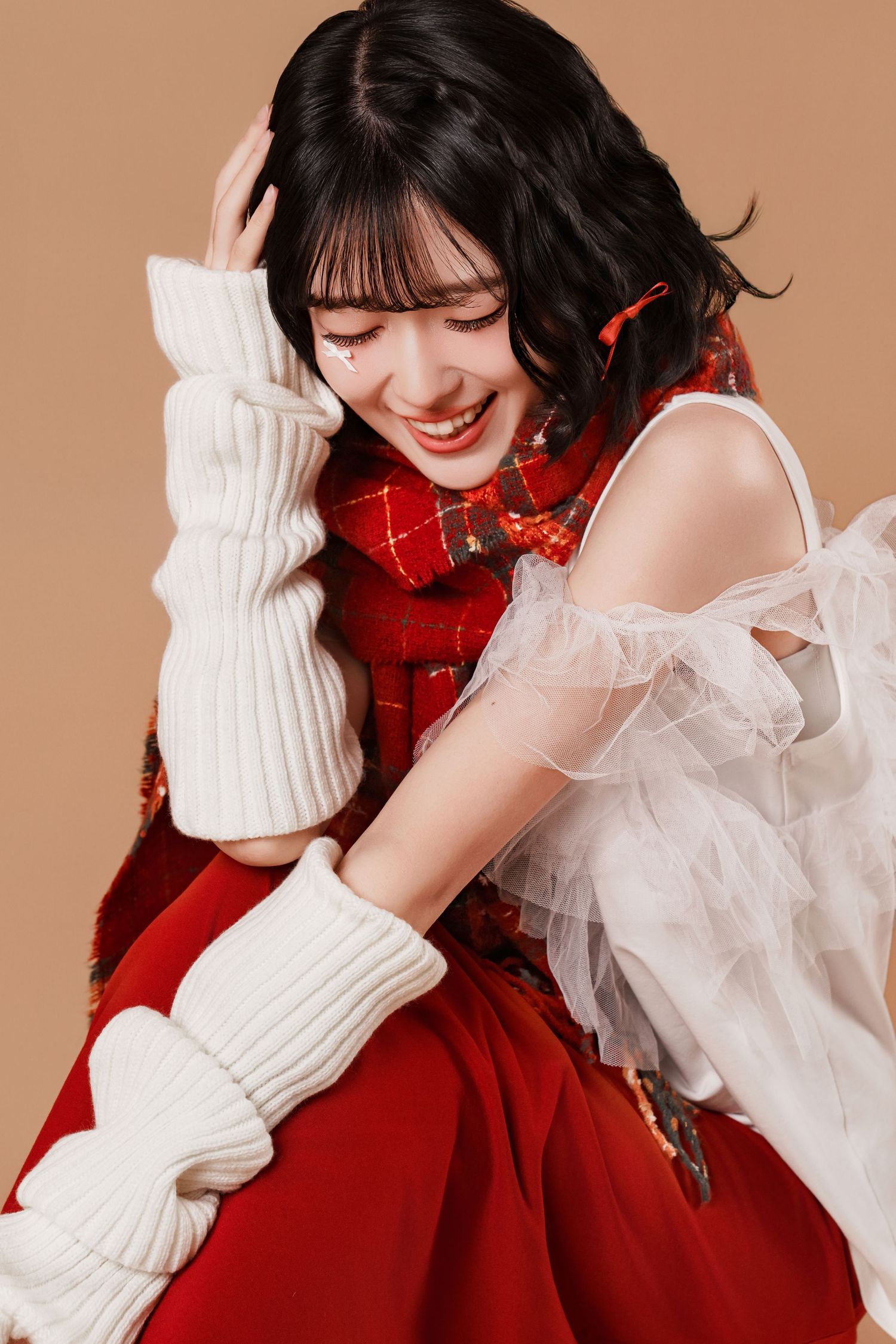 A joyful moment captured in a festive holiday outfit featuring a red dress, white knit accessories and delicate tulle details.
