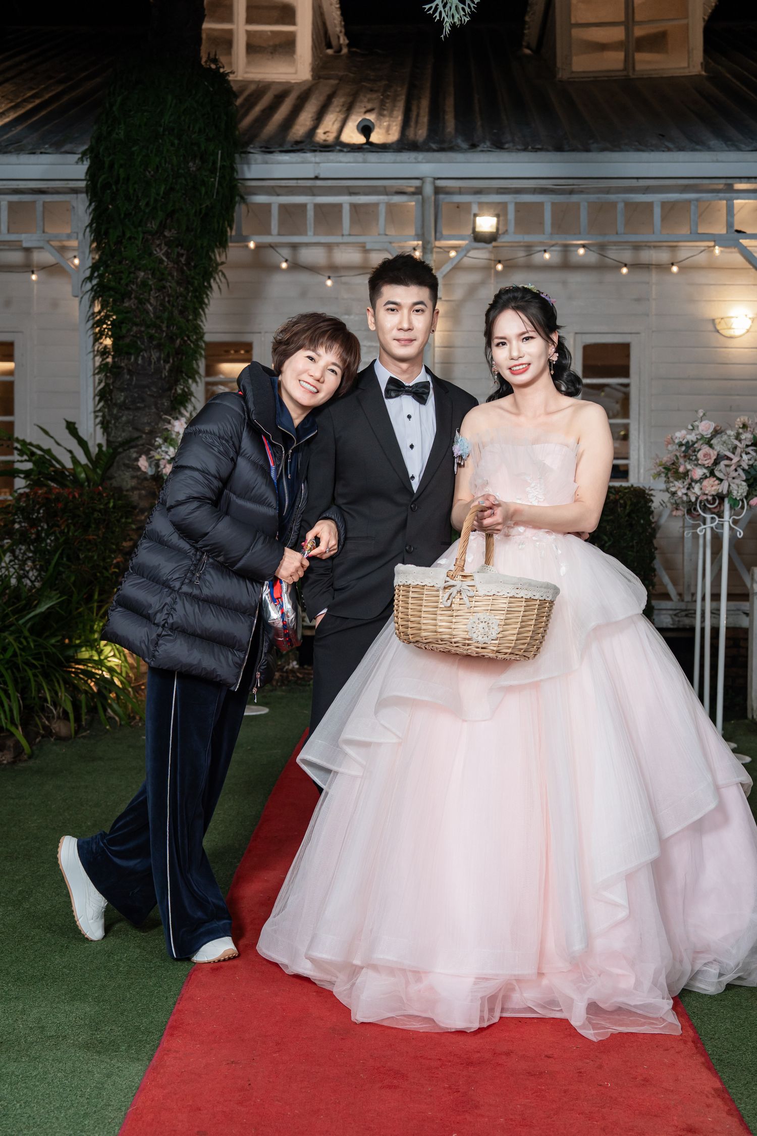 Three photos of a couple in formal wedding attire posing playfully on a red carpet with a wicker basket.