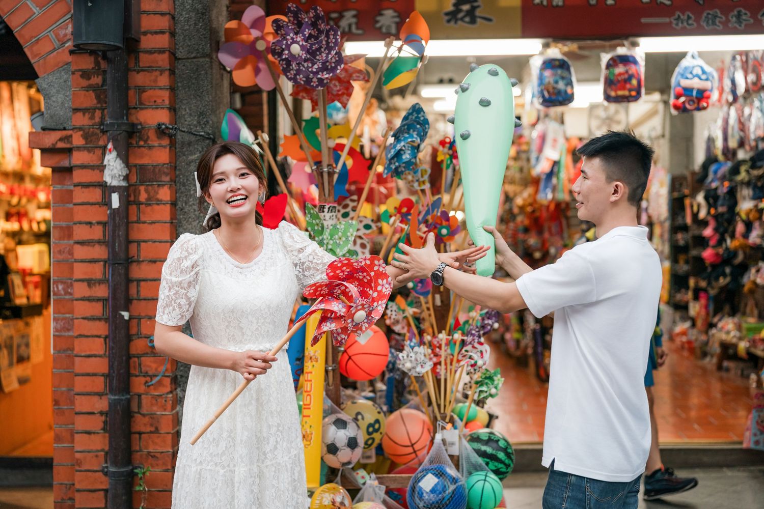 People in white shirts pose and take photos in front of colorful Chinese New Year decorations at a shopping mall.