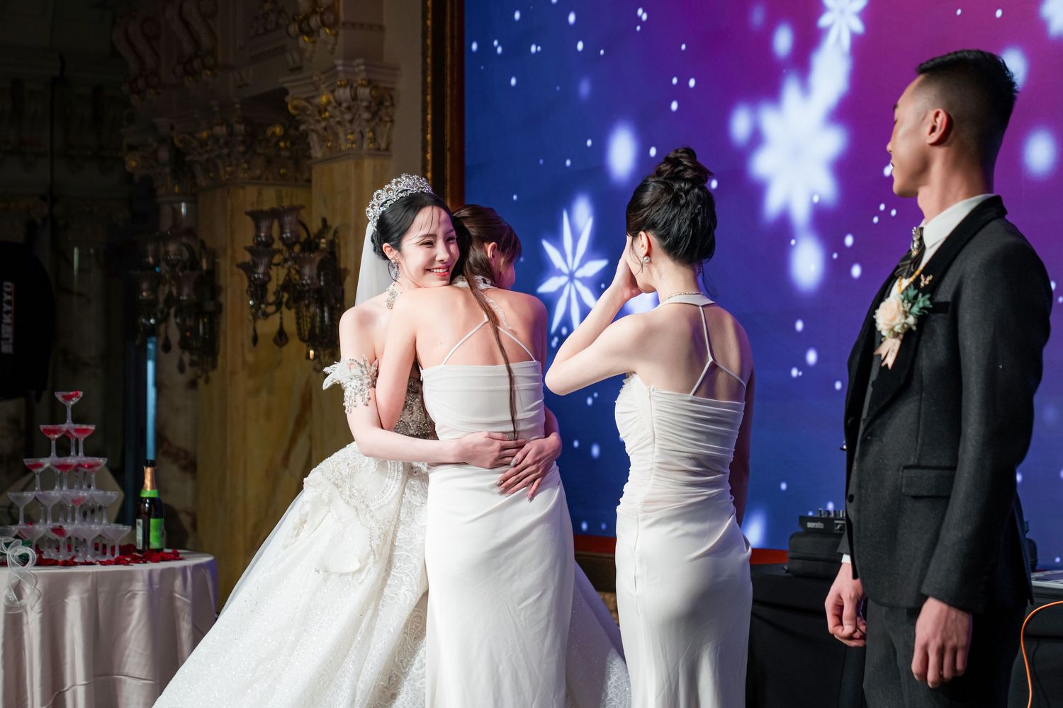 Wedding reception scene with decorative cake table and blue starry backdrop during an emotional celebration moment.