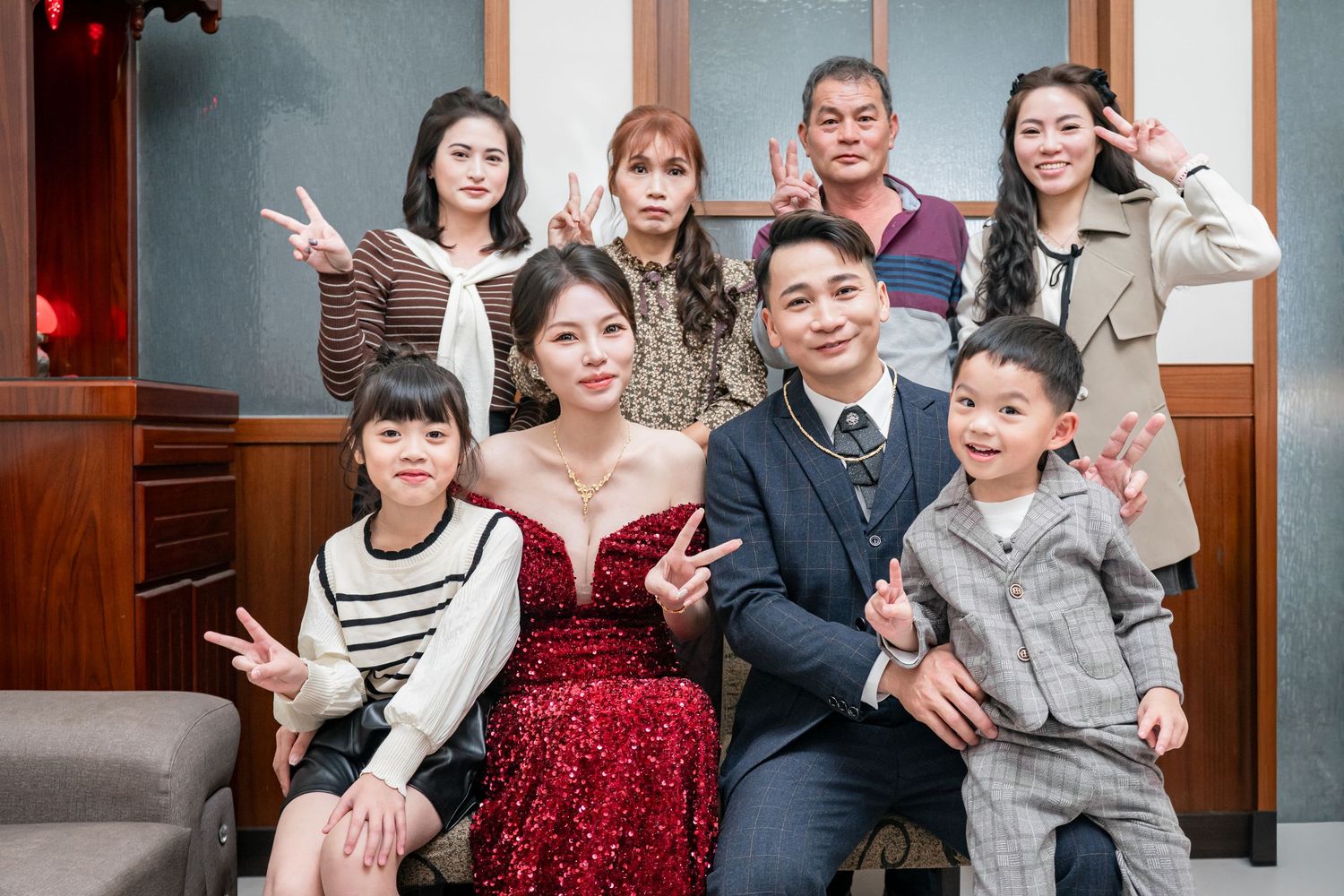 A group poses together in formal attire at an indoor event space with wooden doors in the background.