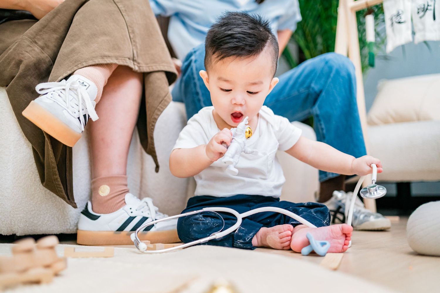 Small child in white shirt plays with toy blocks and educational materials on a light colored surface.