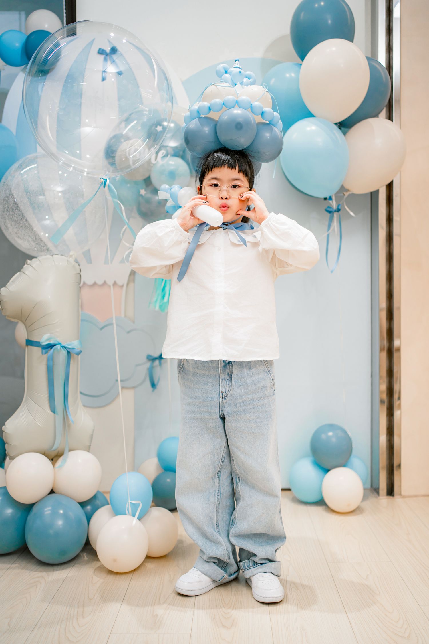 Festive blue and white balloons create a dreamy party backdrop against a light colored wall and floor.