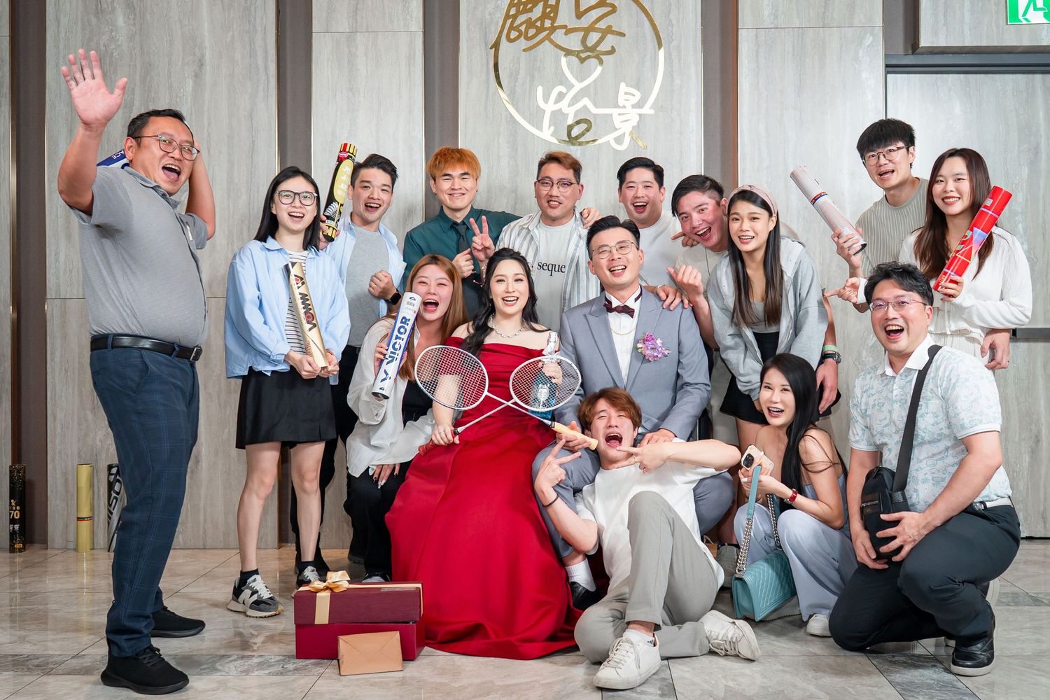 A group gathers for a celebration at an event venue with someone in a red formal dress at the center.