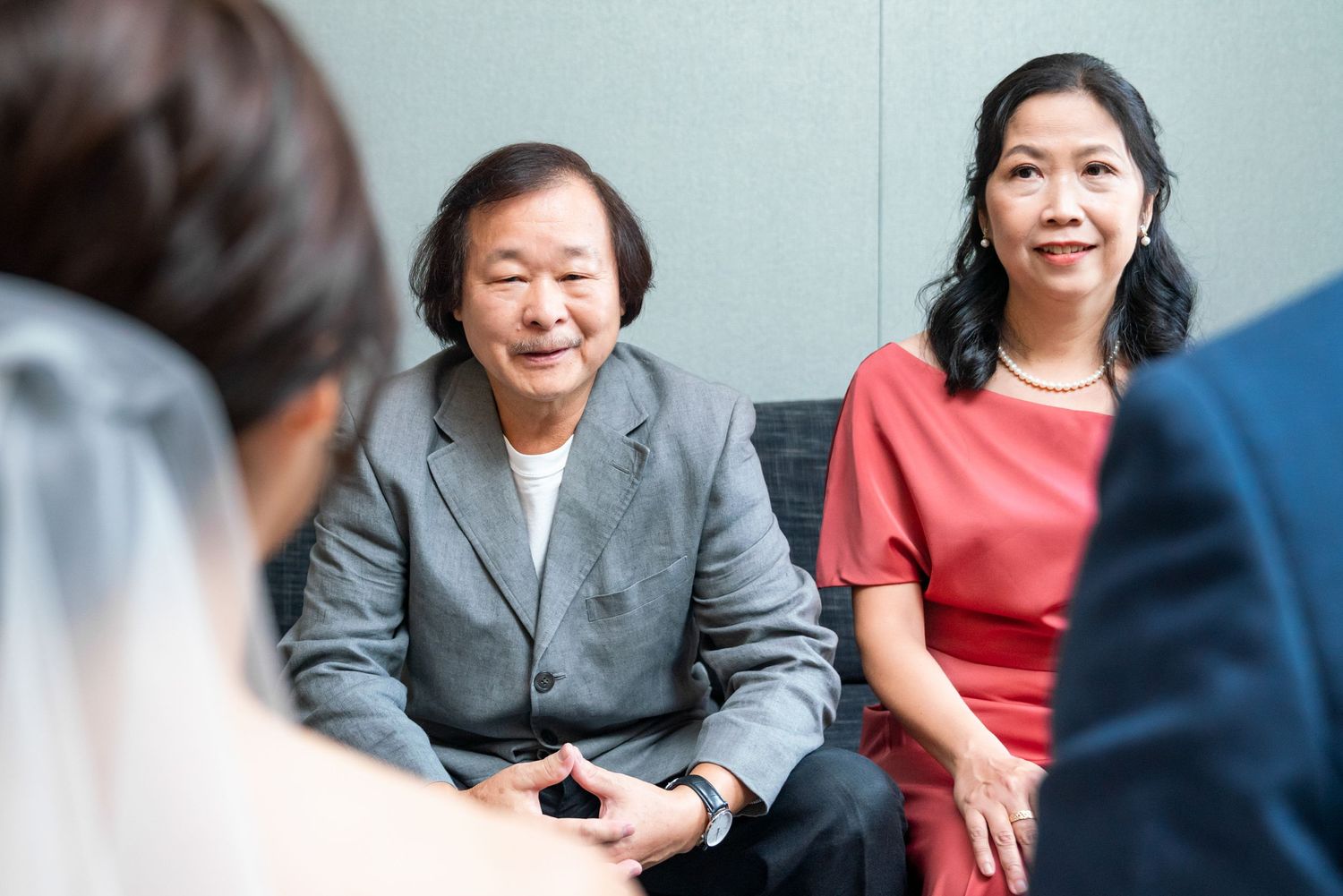 Two people in professional attire smile while seated during what appears to be a business meeting.