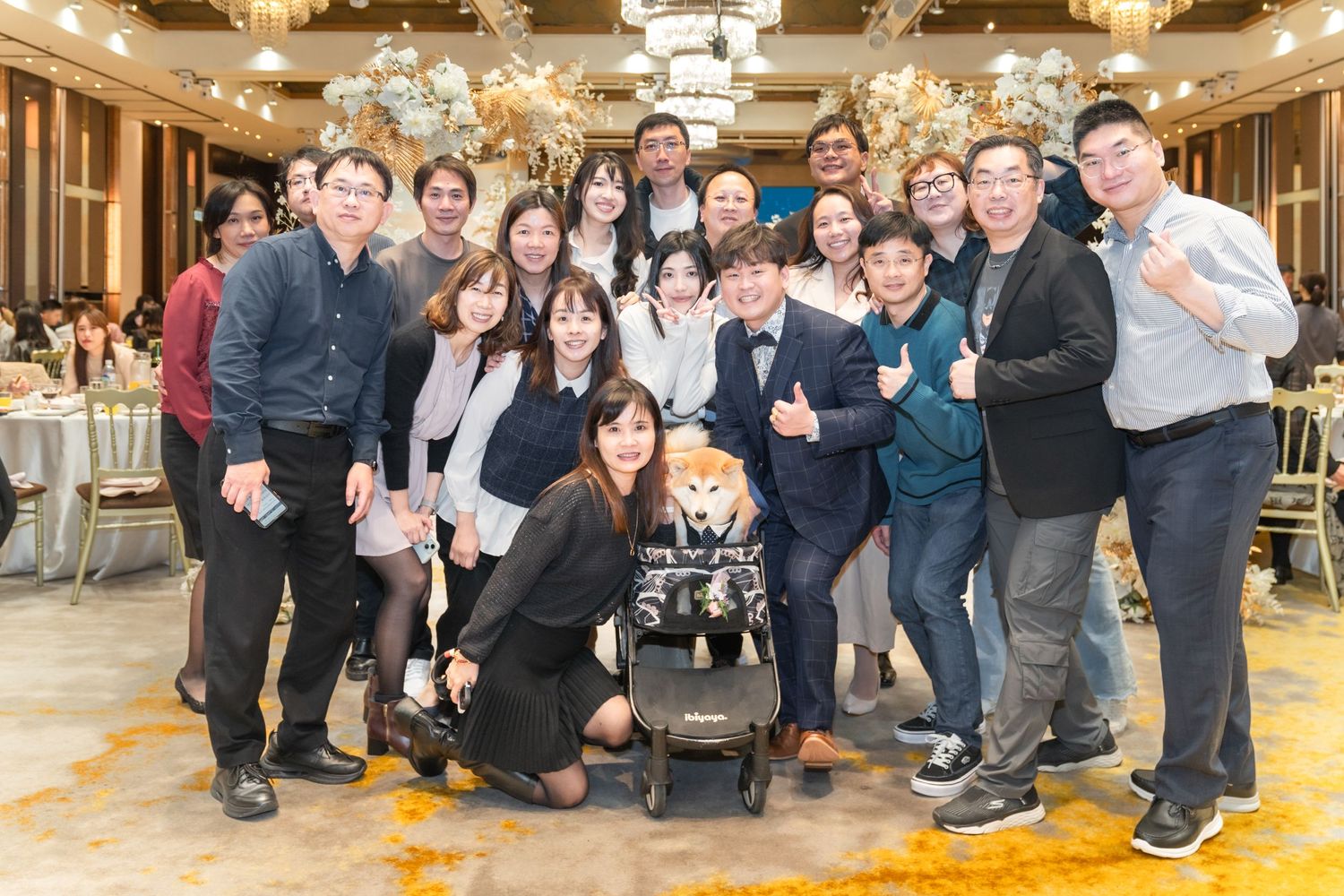 A group of people gathered together posing for a celebratory photo in an elegant ballroom setting.