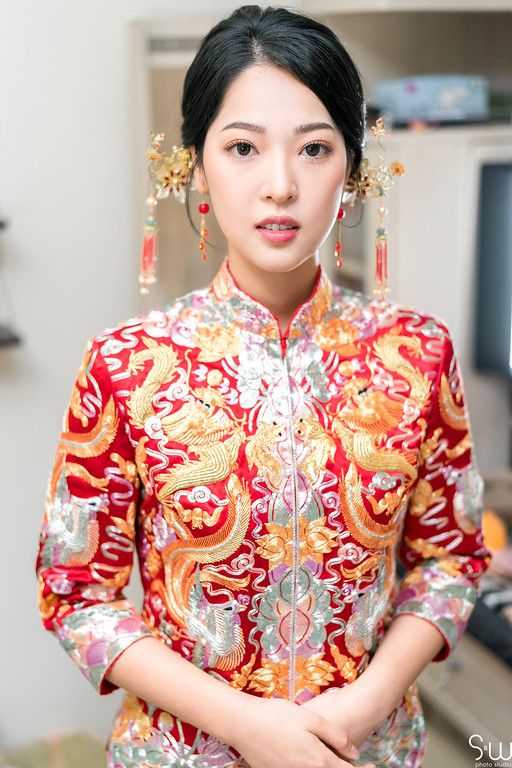 Close-up of traditional Chinese bridal attire with red and gold dragon embroidery and ornate hair accessories.