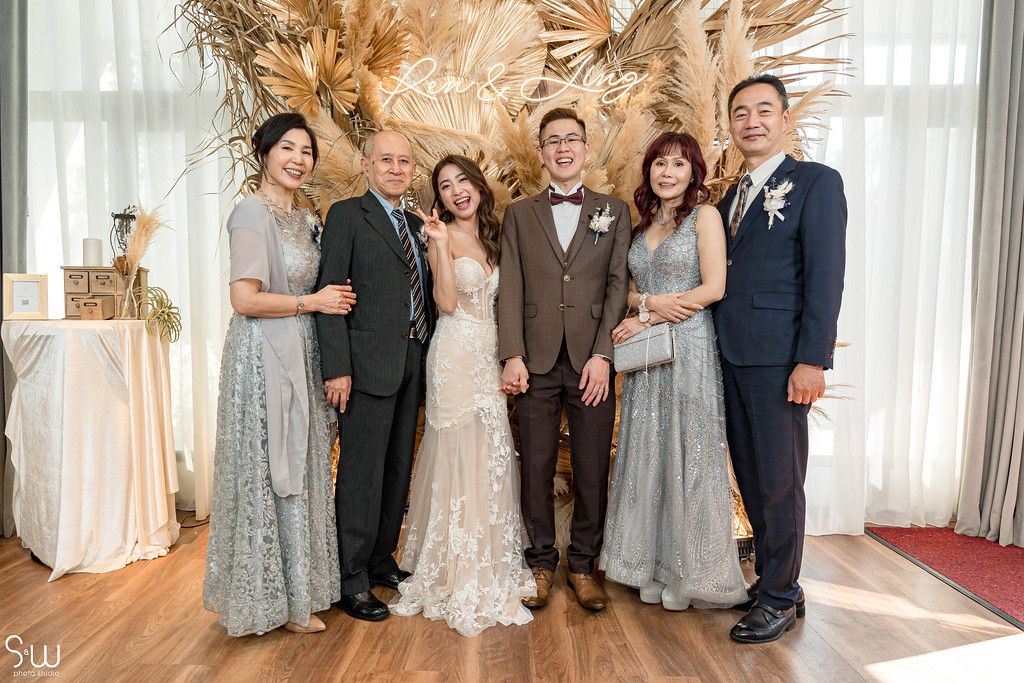 Formal wedding party portrait with elegant decor and dried pampas grass backdrop.