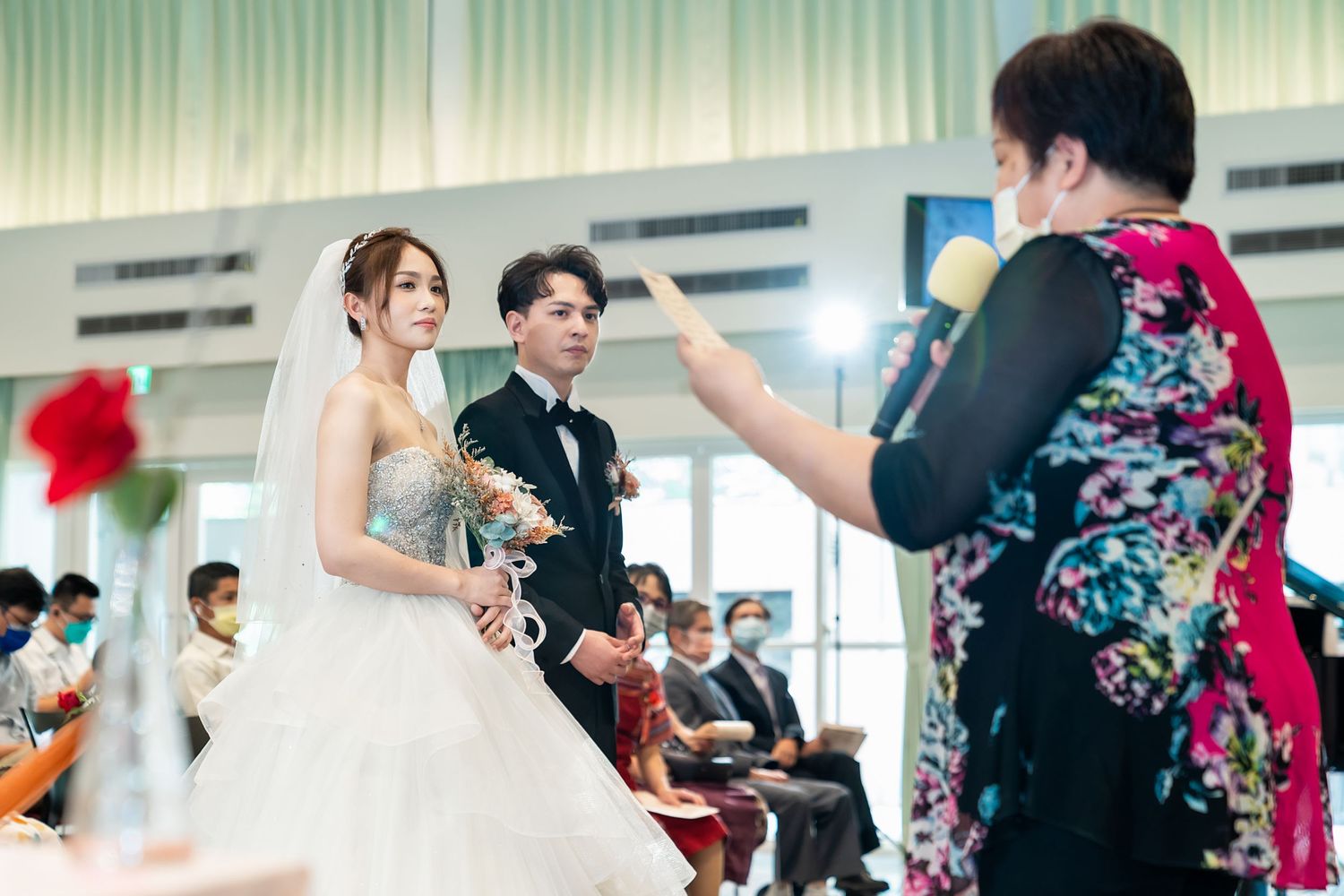Wedding ceremony with couple being photographed in front of seated guests.