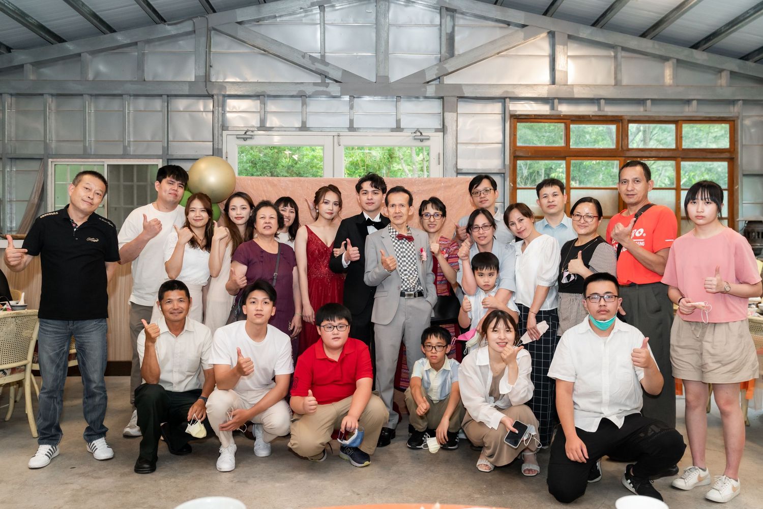 Large group photo of event attendees in casual and formal wear in a bright indoor space.